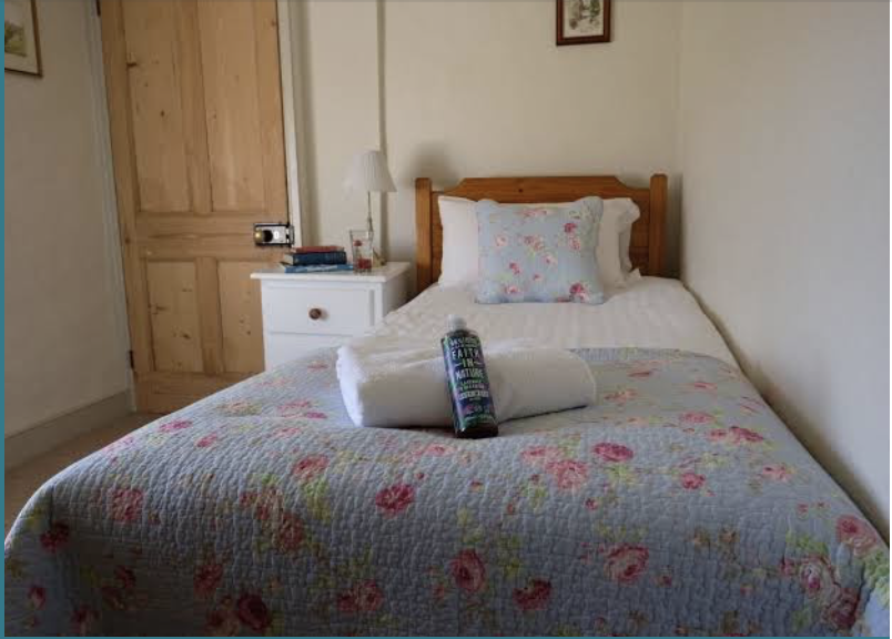 Bedroom with a white bed, wooden beams, and a white chest of drawers.