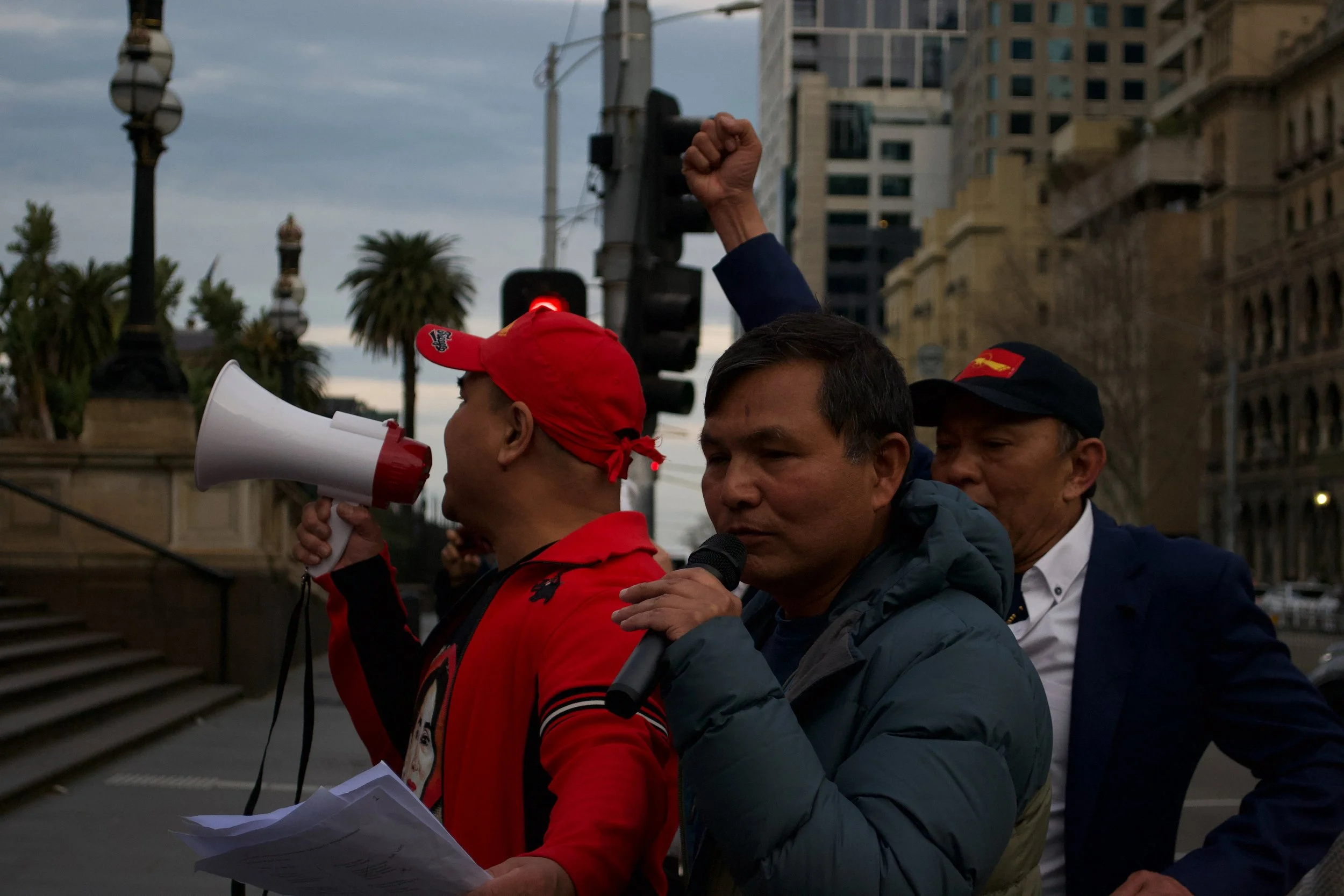 Speakers make an announcement to the crowd while another man holds up a fist 06.09.2025