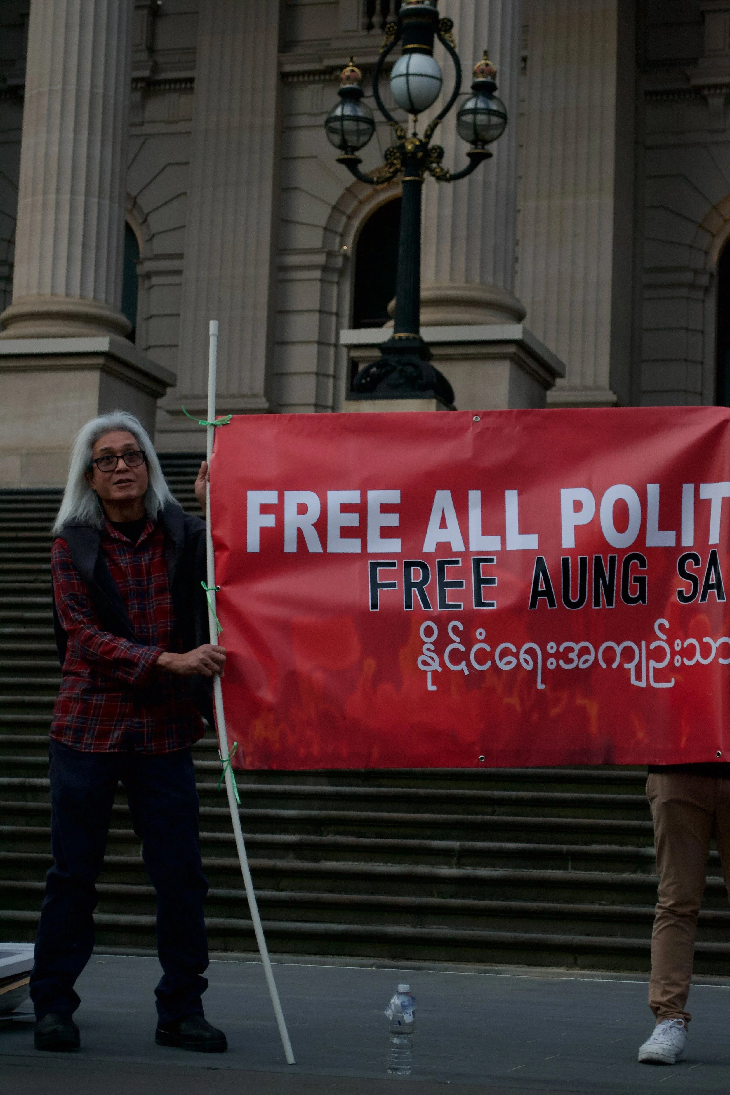 A man listens to a speaker while holding up a banner 06.09.2025