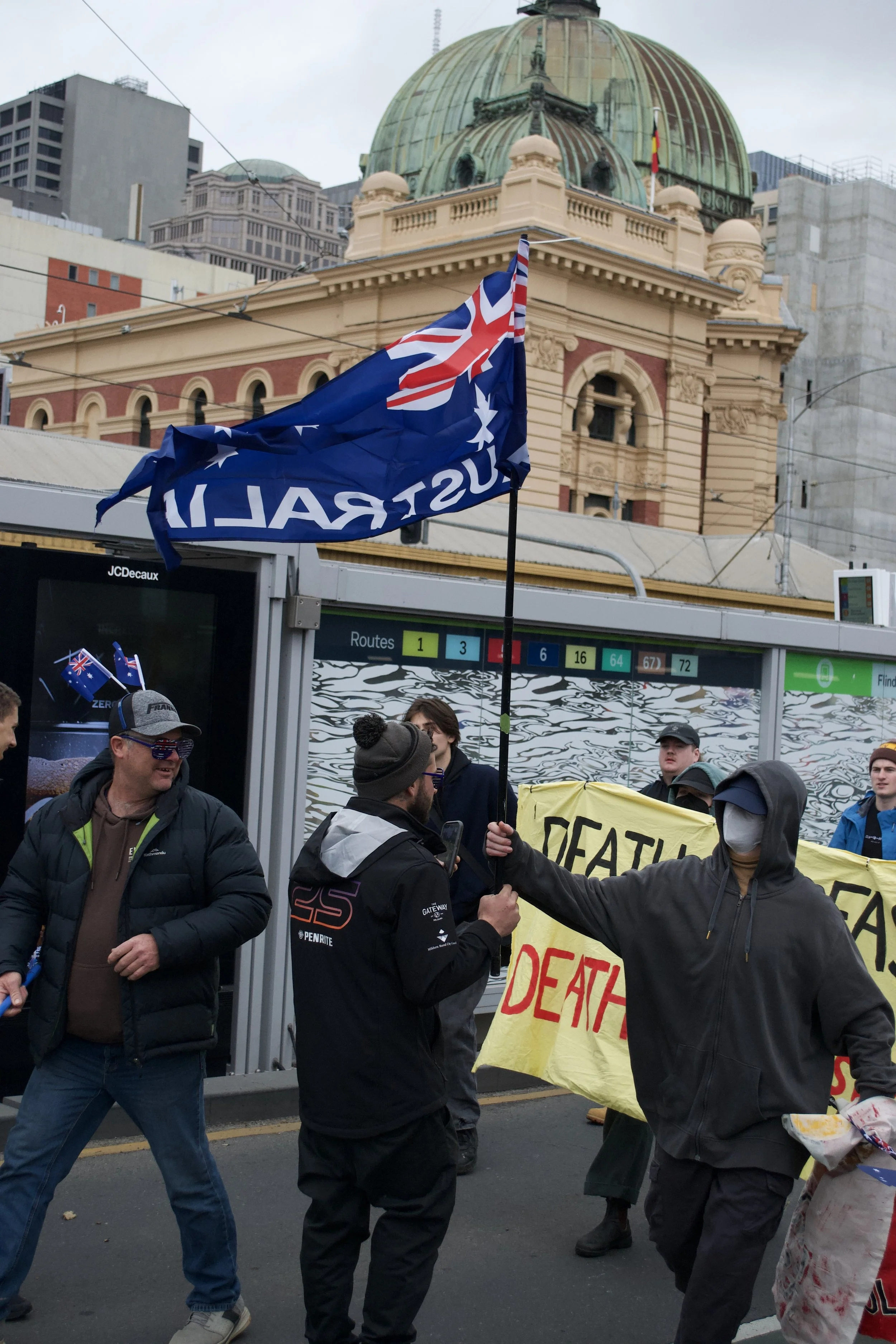 A counter protester grabs the Australian Flag out of a 'March for Australia' protesters hand after they mistakenly made their way toward the counter protester at Flinders Street Tram Stop.