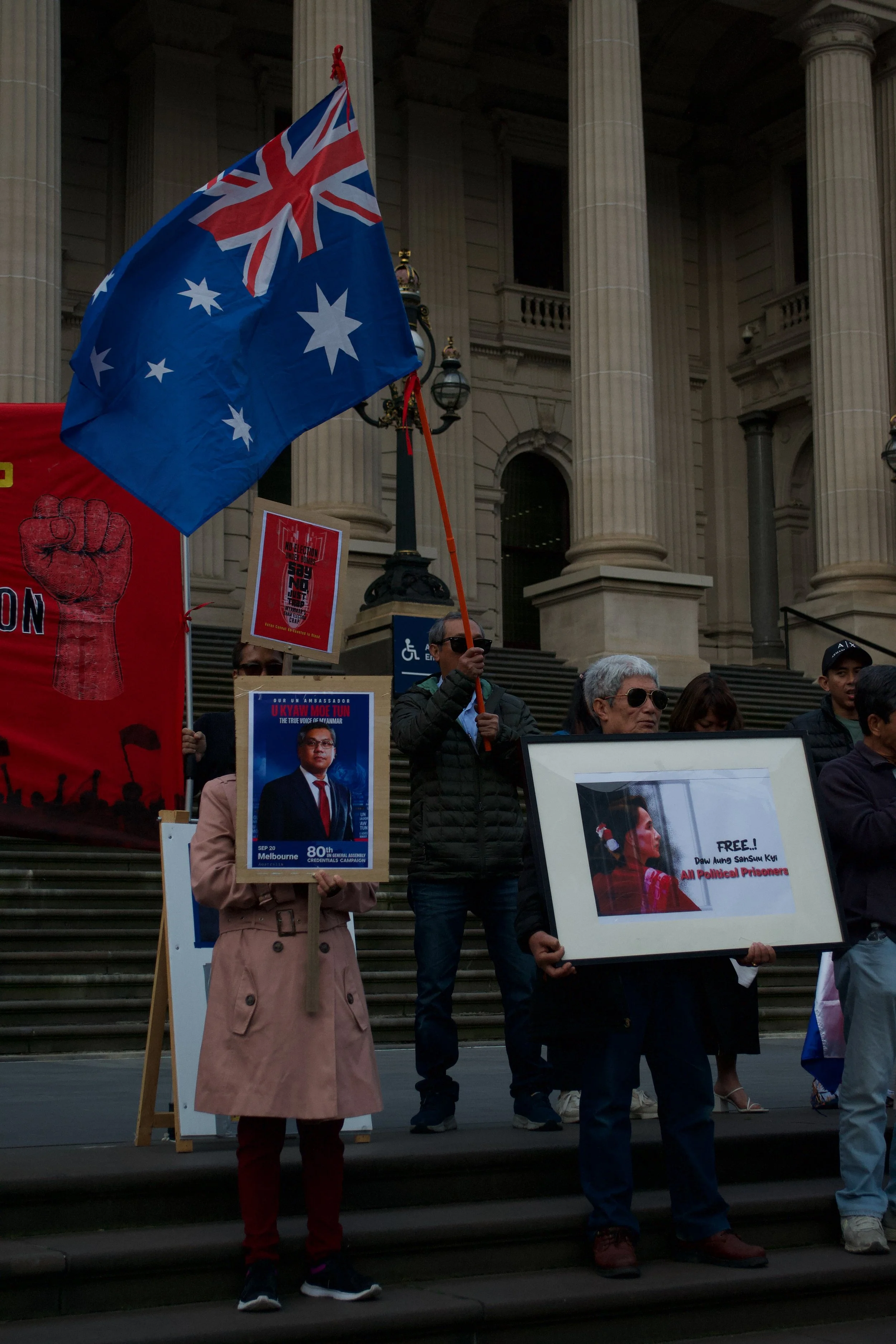 Protesters hold up signs while one waves the Australian flag 06.09.2025