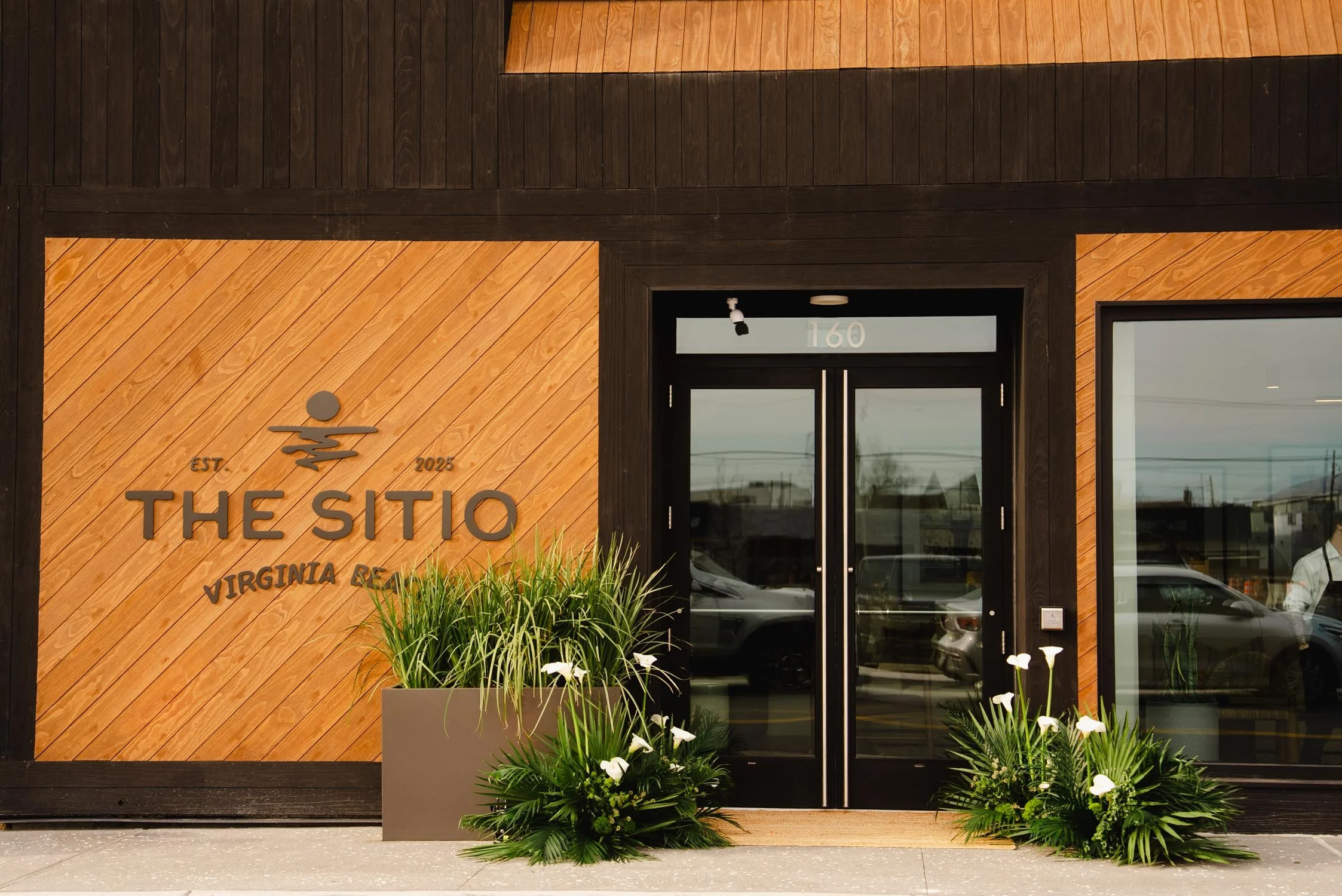 The Sitio entrance with logo signage and wood-paneled exterior at boutique hotel in Virginia Beach