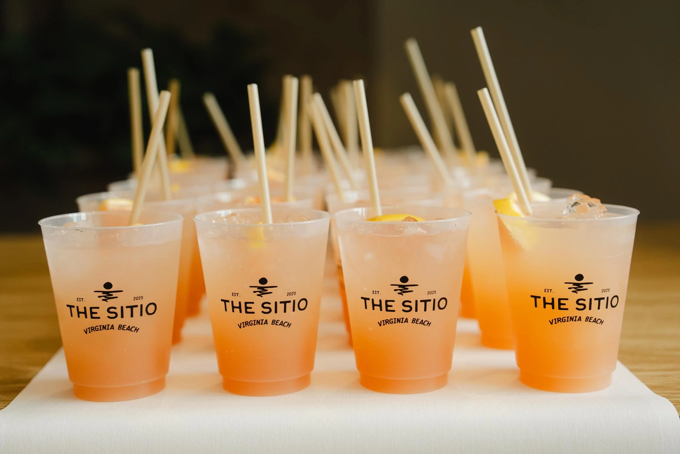 Tray of branded cocktails with The Sitio logo on plastic cups at a hotel event in Virginia Beach