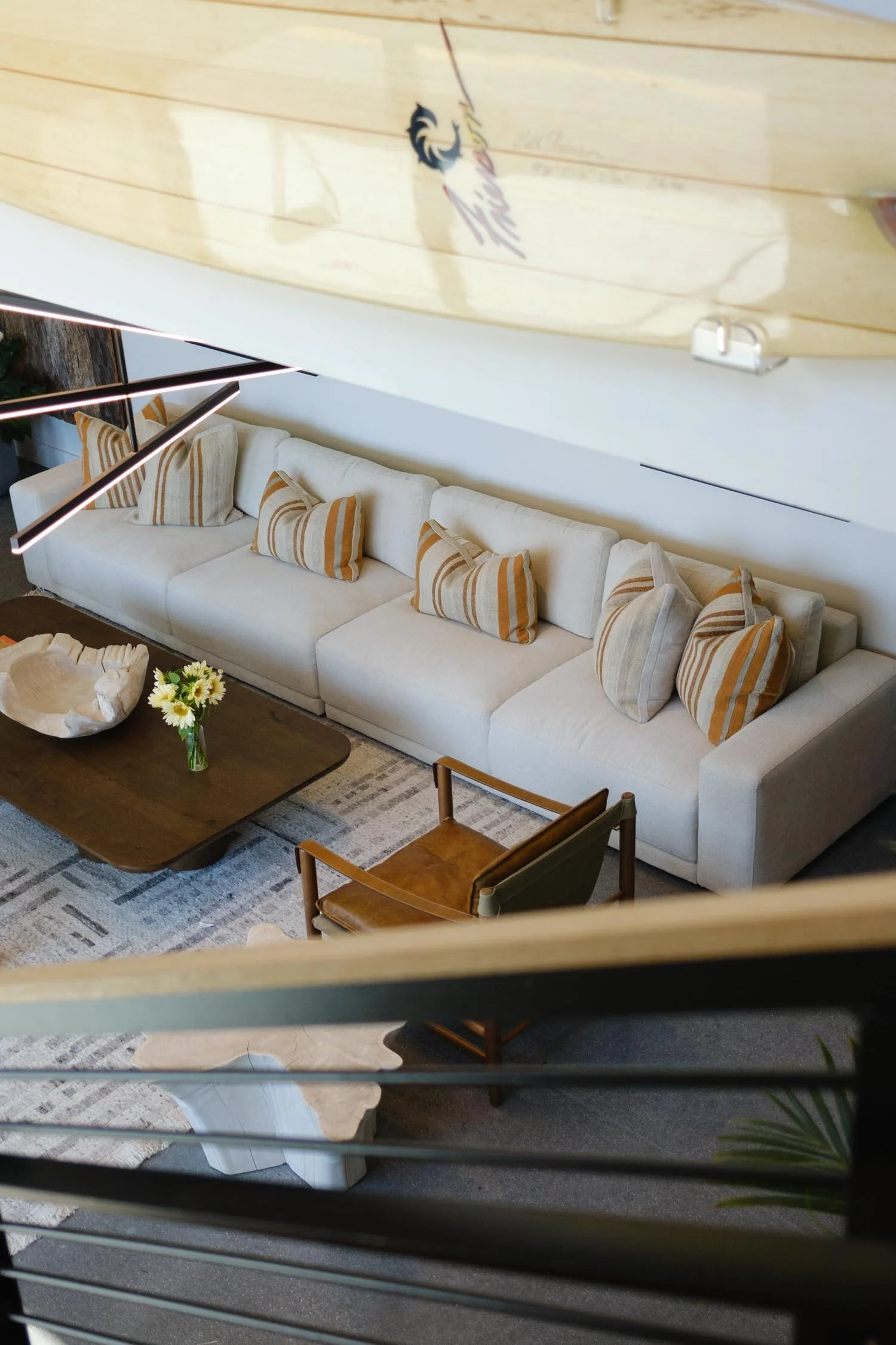 View from the upper floor down into the common lounge at The Sitio with a long couch and coastal interiors