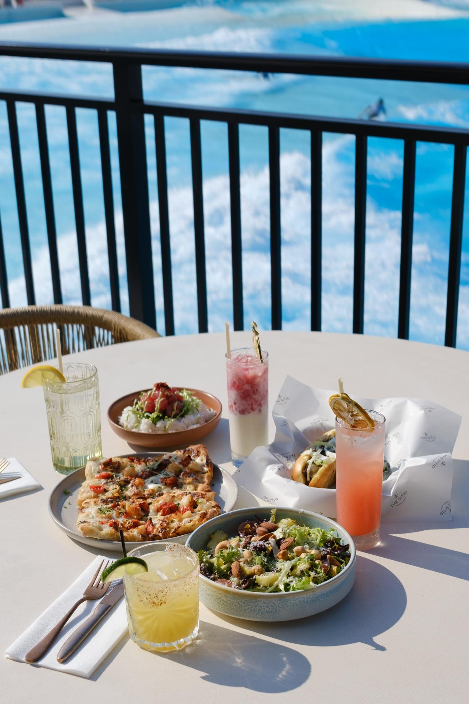 Breakfast items and cocktails on a table by the pool at The Sitio Atlantic Park