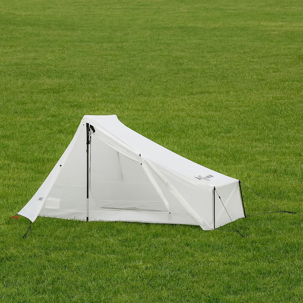 Tente blanche sur une grande étendue d'herbe verte.