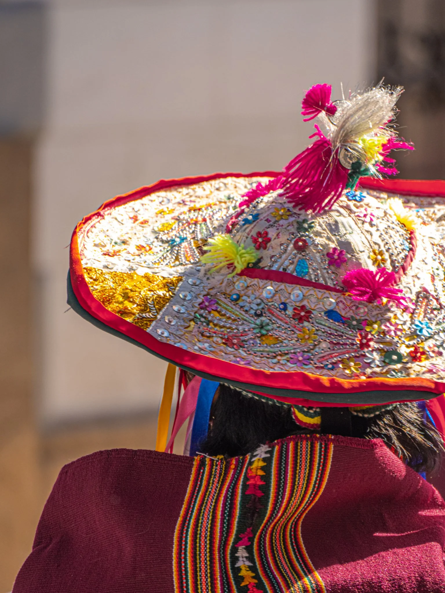 Chapeau coloré et orné porté par une personne habillée en vêtement traditionnel, vue de derrière