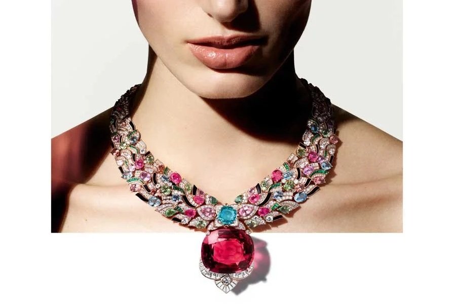 Woman wearing the Bvlgari Celestial Mosaic high jewellery necklace with large crimson spinel centre stone and vibrant coloured gemstones, elegantly draped around the neckline.