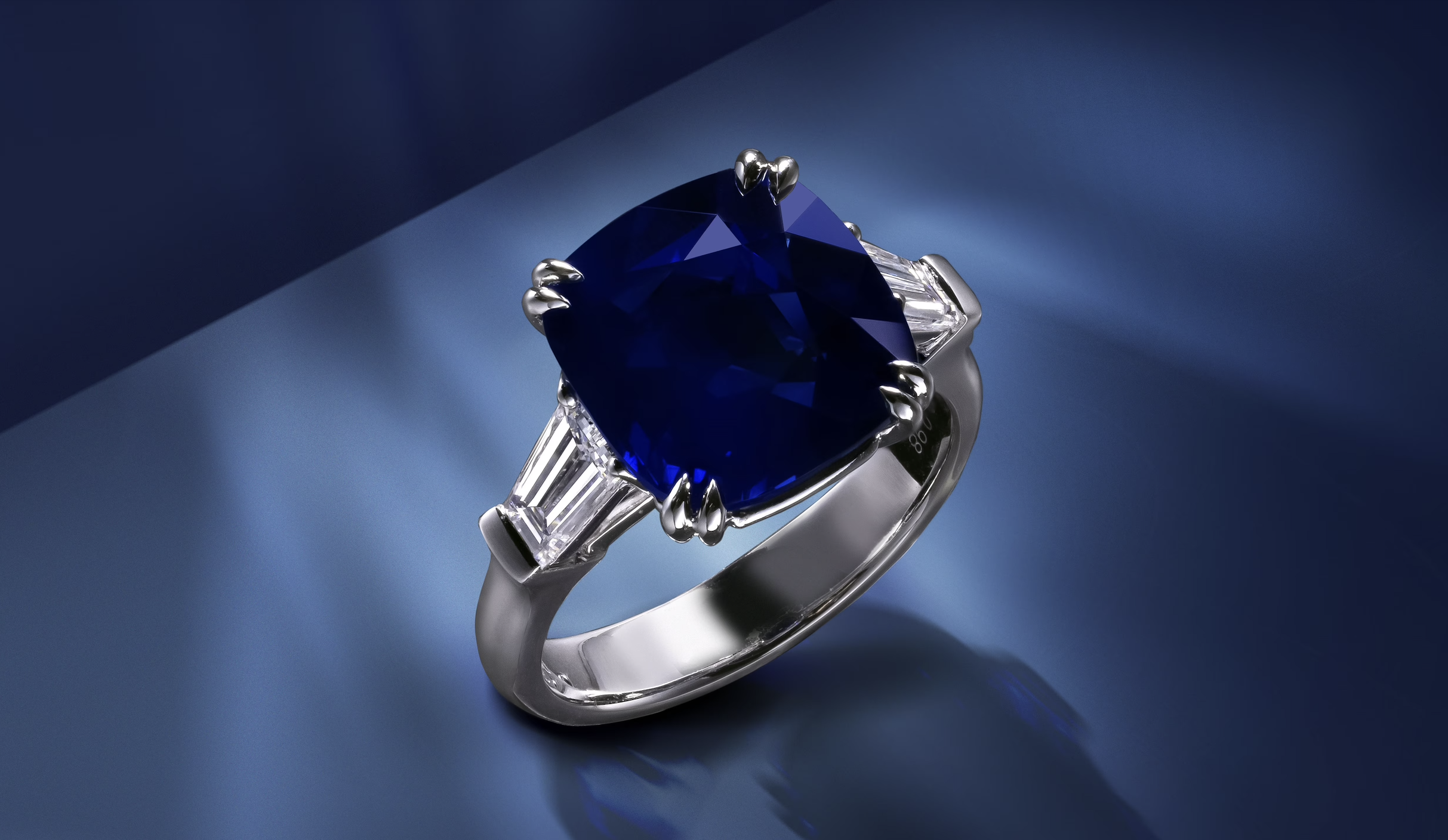Luxury ring featuring a vivid Kashmir sapphire at the centre, flanked by two colourless diamonds on each side, showcasing the rich velvety blue colour characteristic of Kashmir sapphires.