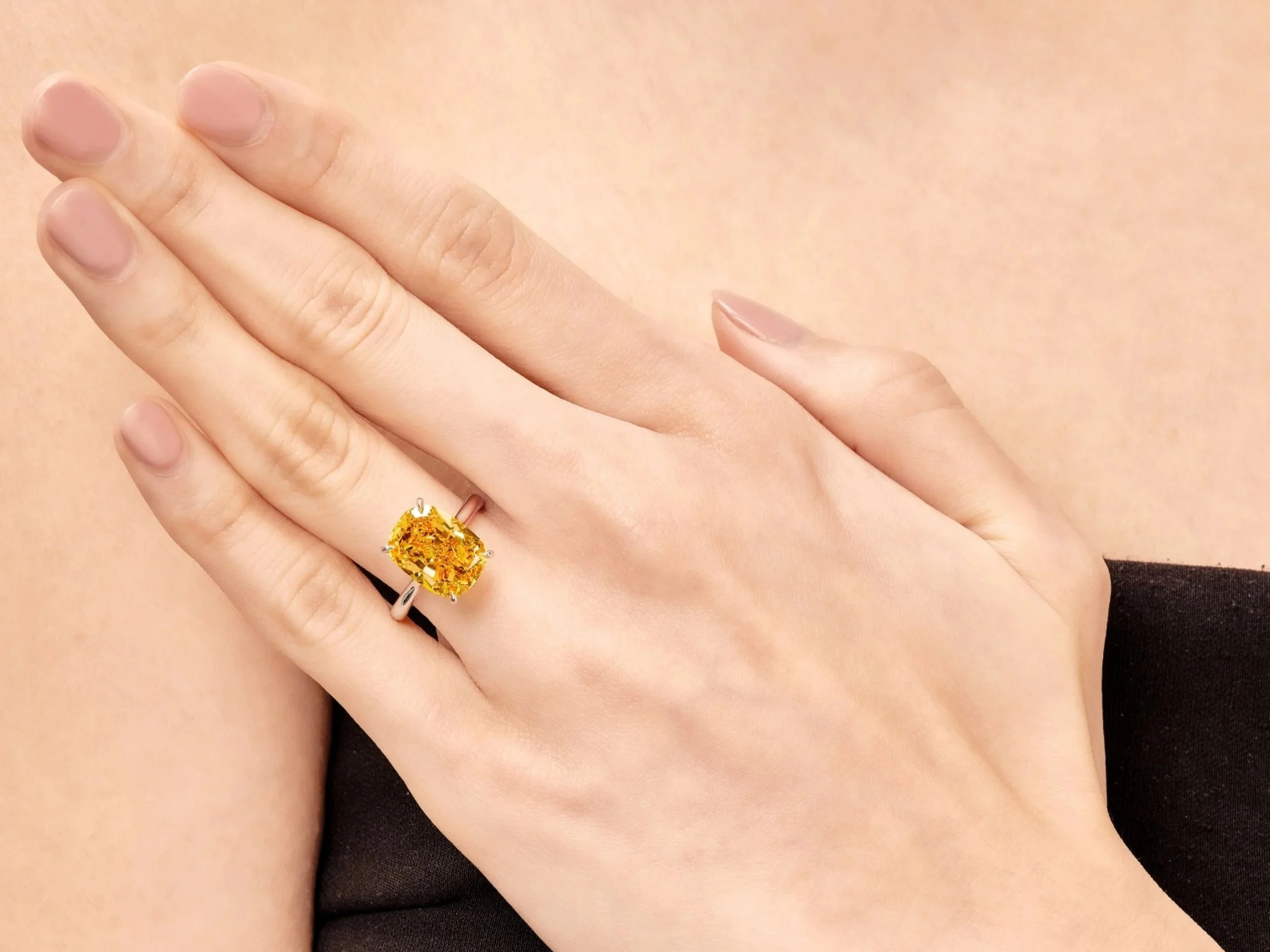 Fancy vivid orange diamond set in a ring, displayed at a Sotheby’s auction, featuring an intense pure orange pear shaped stone mounted in a refined platinum setting under professional lighting.