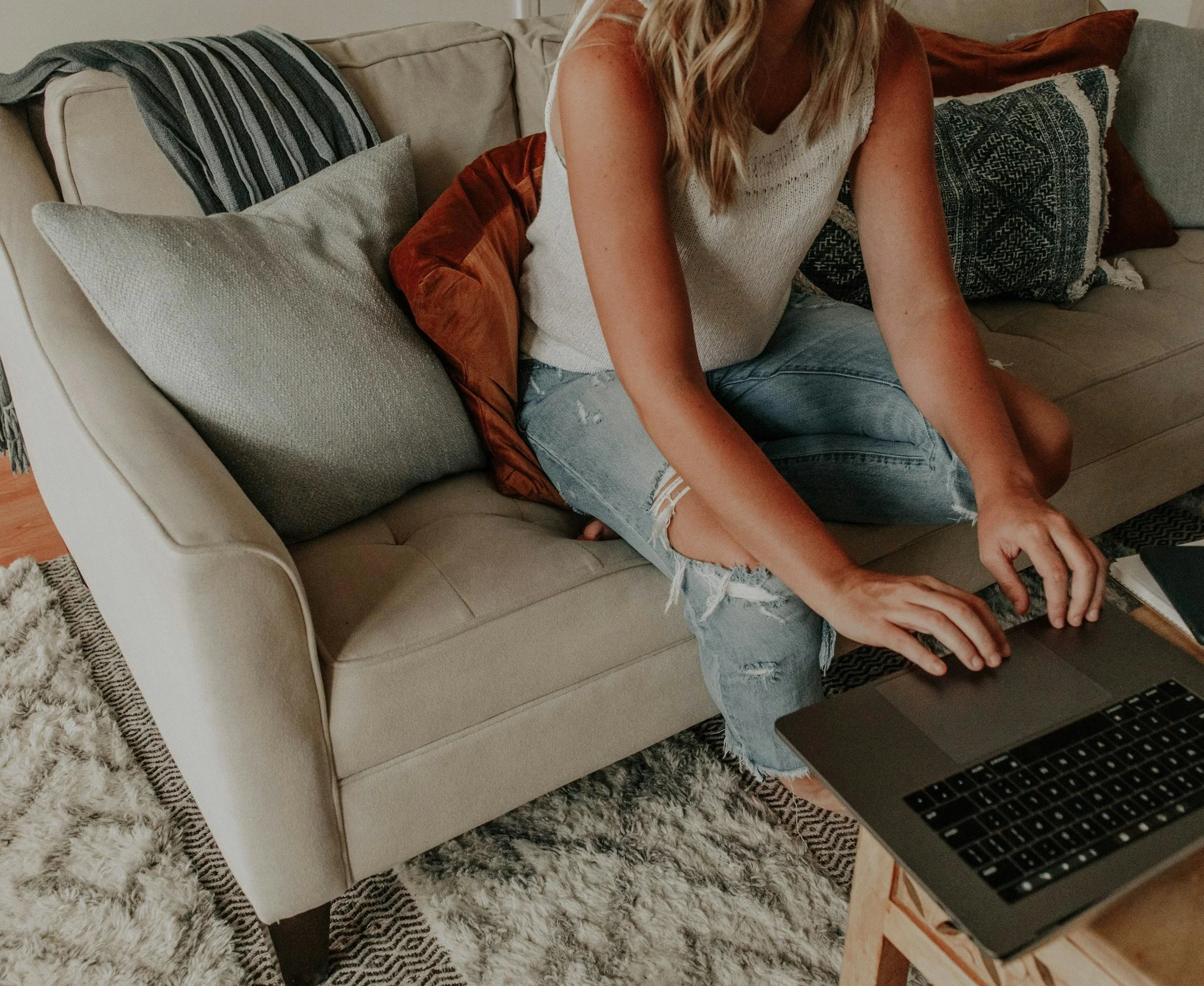 Kvinde der sidder i en sofa og arbejder på sin bærbare computer i forbindelse med online terapeutisk skrivning.