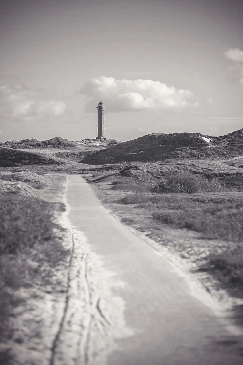Sort/hvidt fotografi af en sti mod et fyrtårn, der symboliserer retning og personligt valg i psykoterapi.