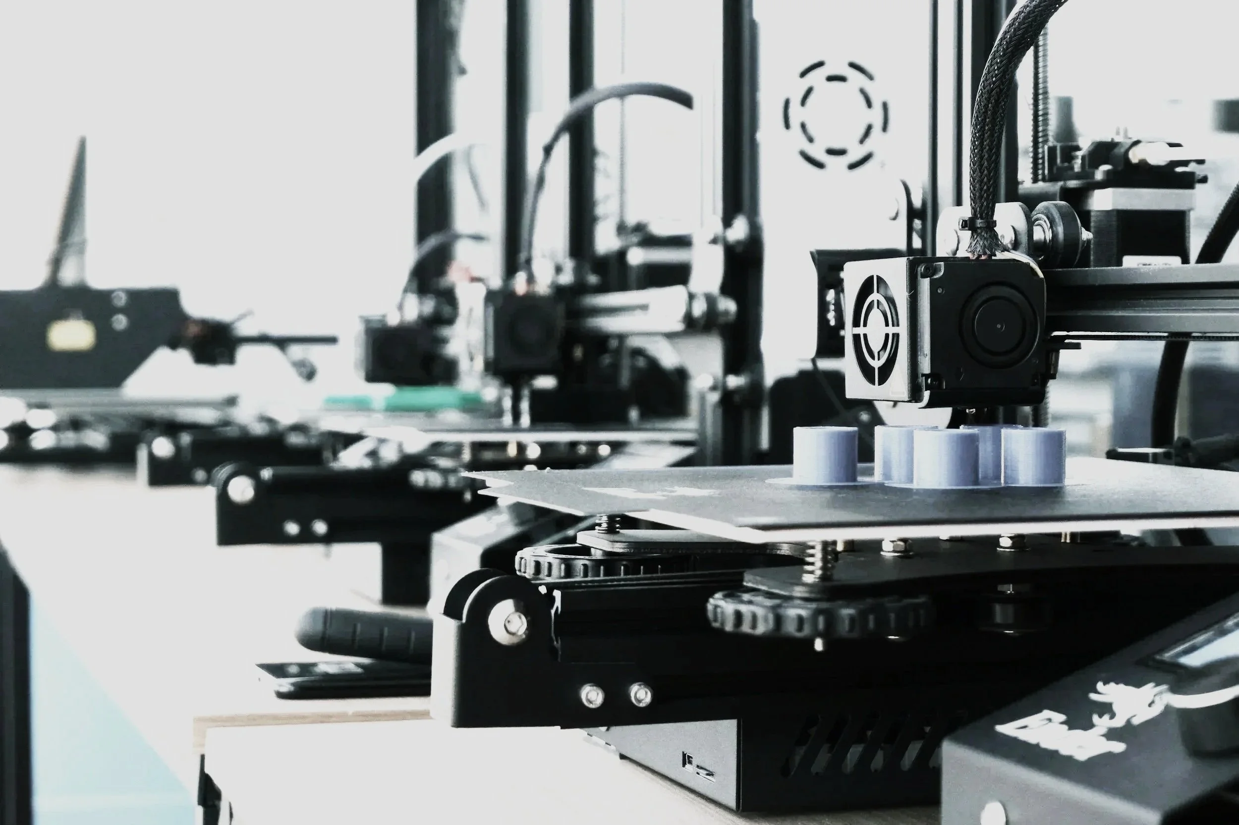 Une imprimante 3D en action avec plusieurs bobines de filament sur la surface de travail.