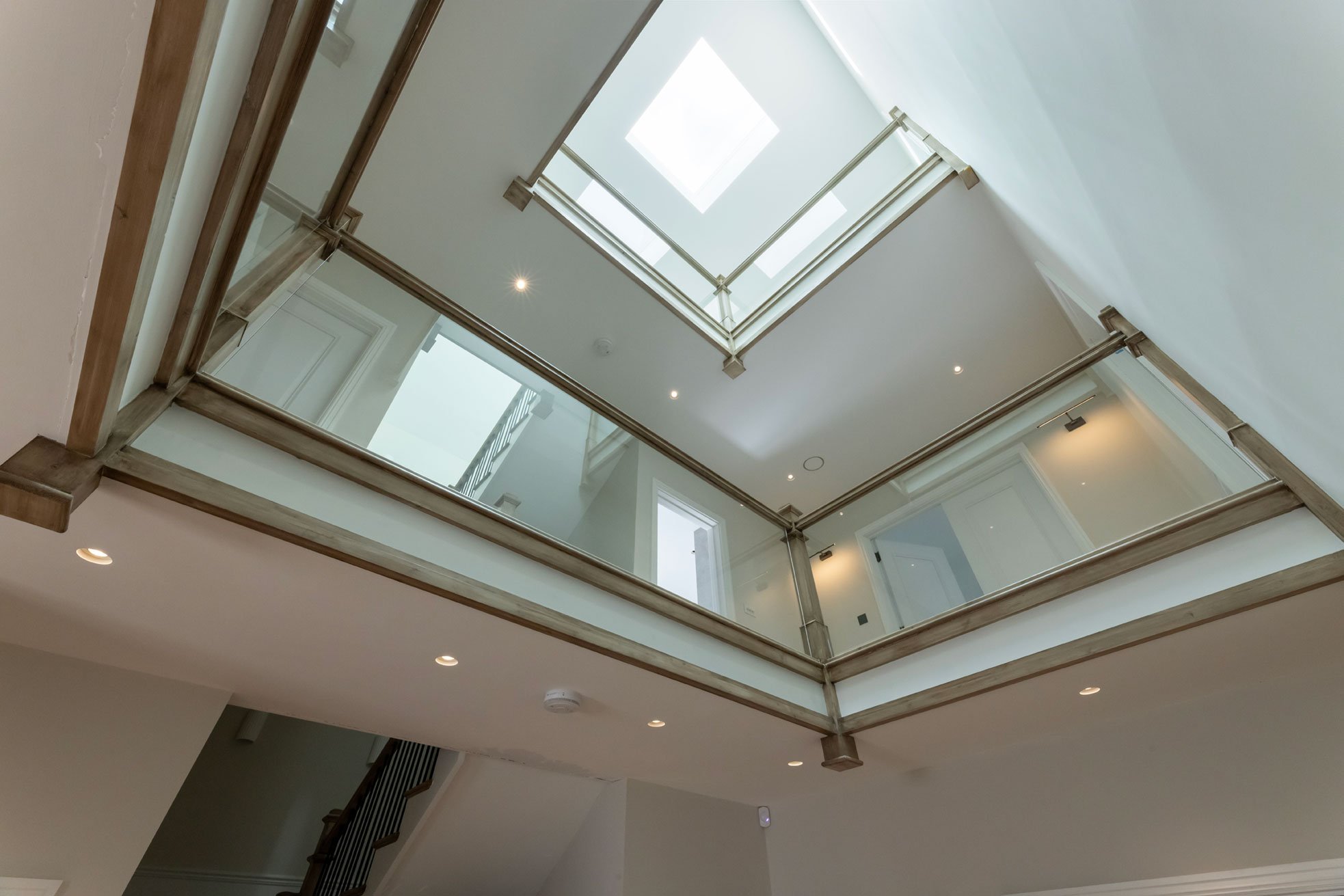 Interior view of a modern multi-story house with glass balconies and skylights, looking upward from the ground floor.