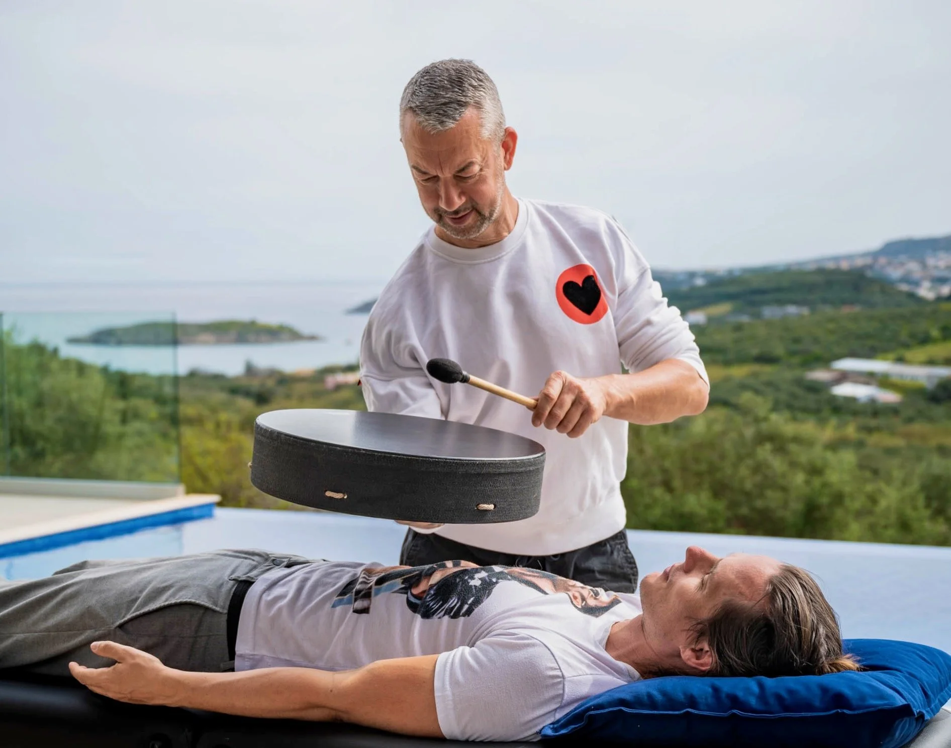 rob sykes sound therapist playing drum over a client in a one-to-one session outside in crete