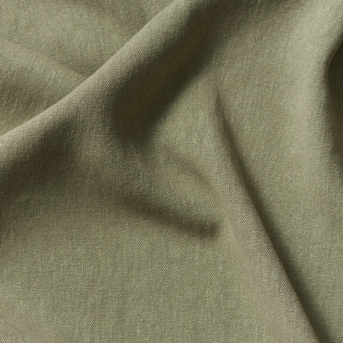 Close-up of olive-green fabric with a smooth texture and slight wrinkles.