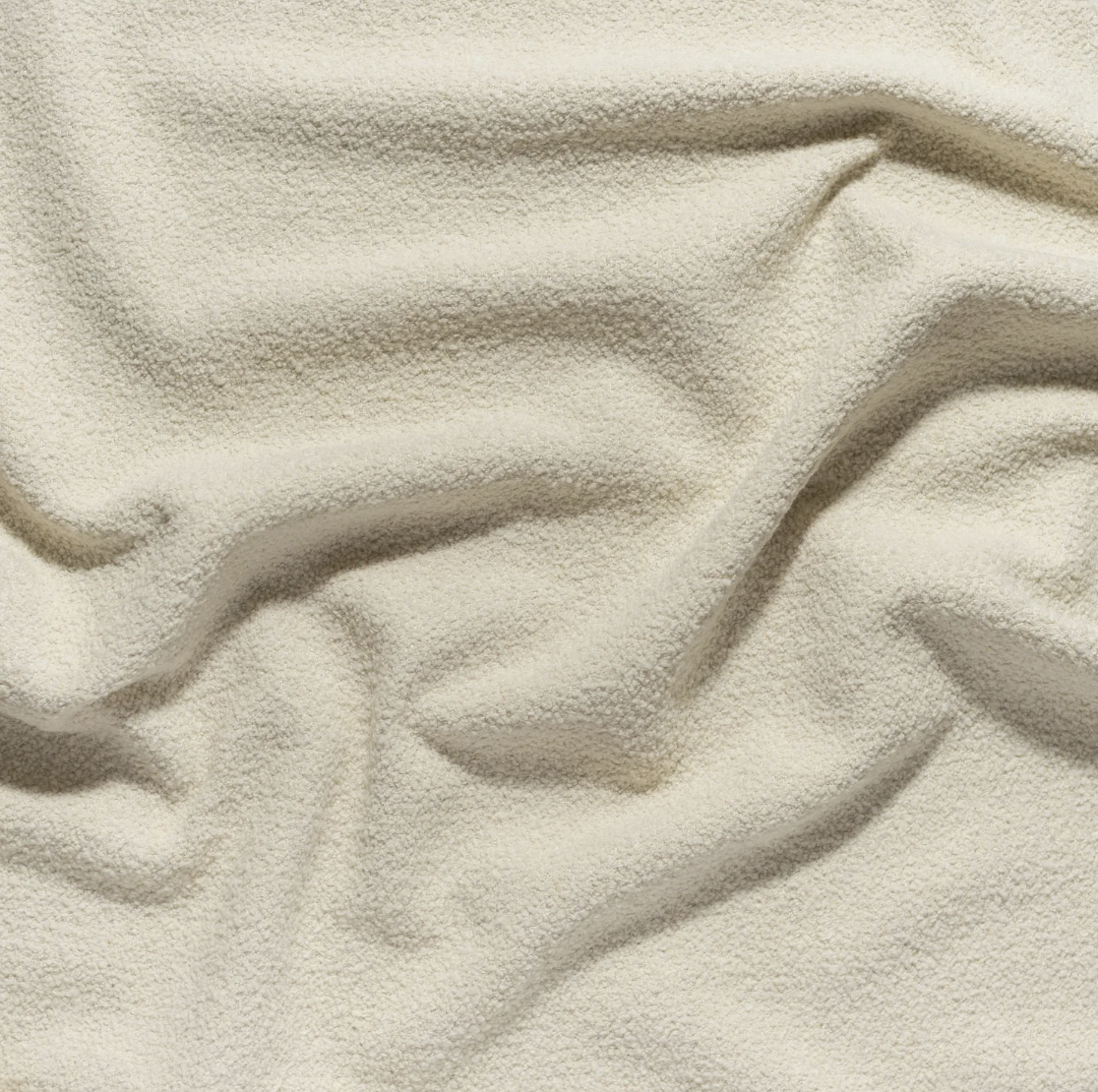 Close-up of a textured, beige fabric with soft folds.