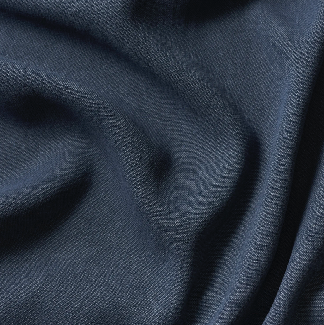 Close-up of dark blue fabric with a textured, woven appearance, slightly crumpled.
