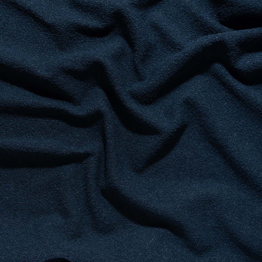 Close-up of dark blue, textured fabric with soft folds and creases.