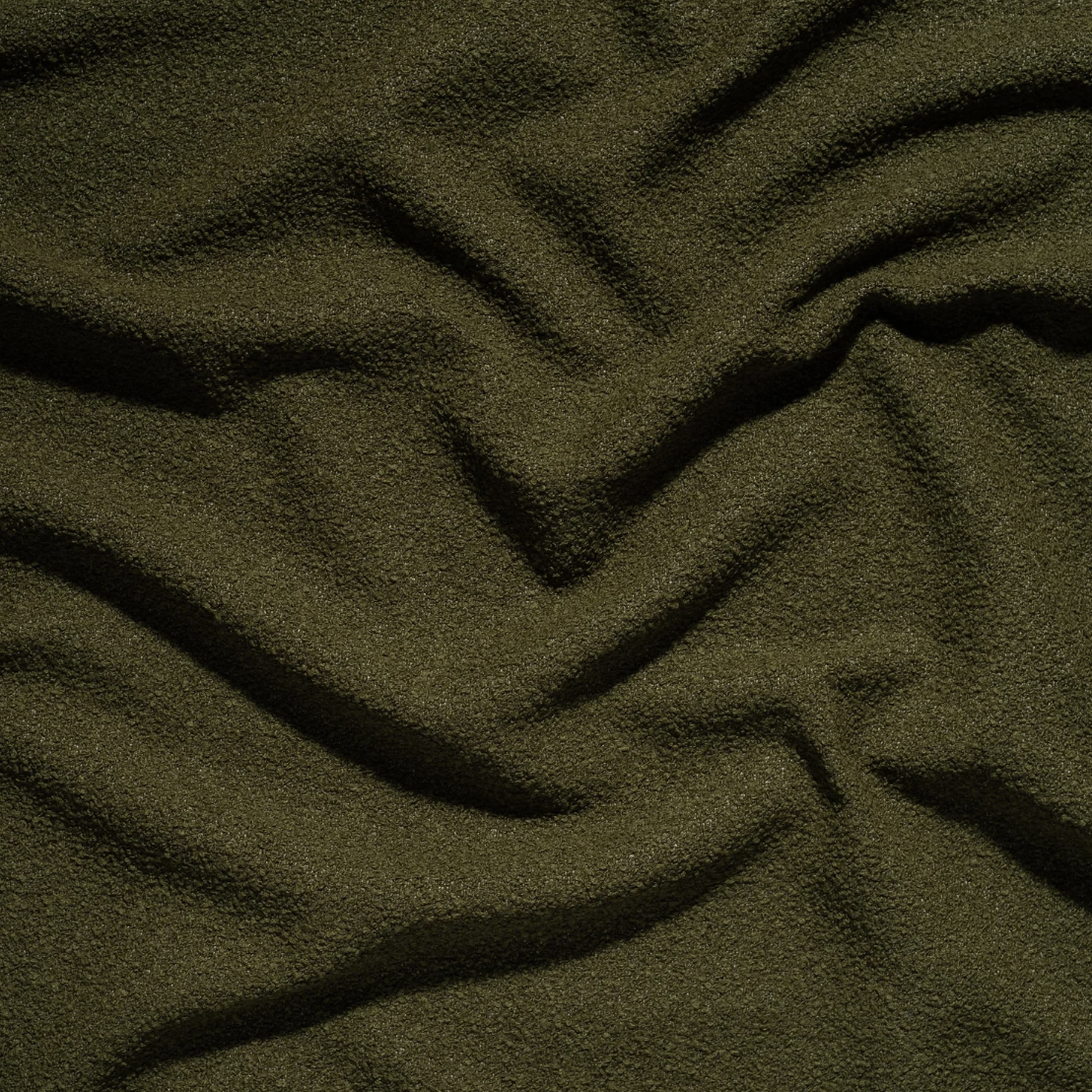 Close-up of green fabric with soft, textured surface and visible embroidery.