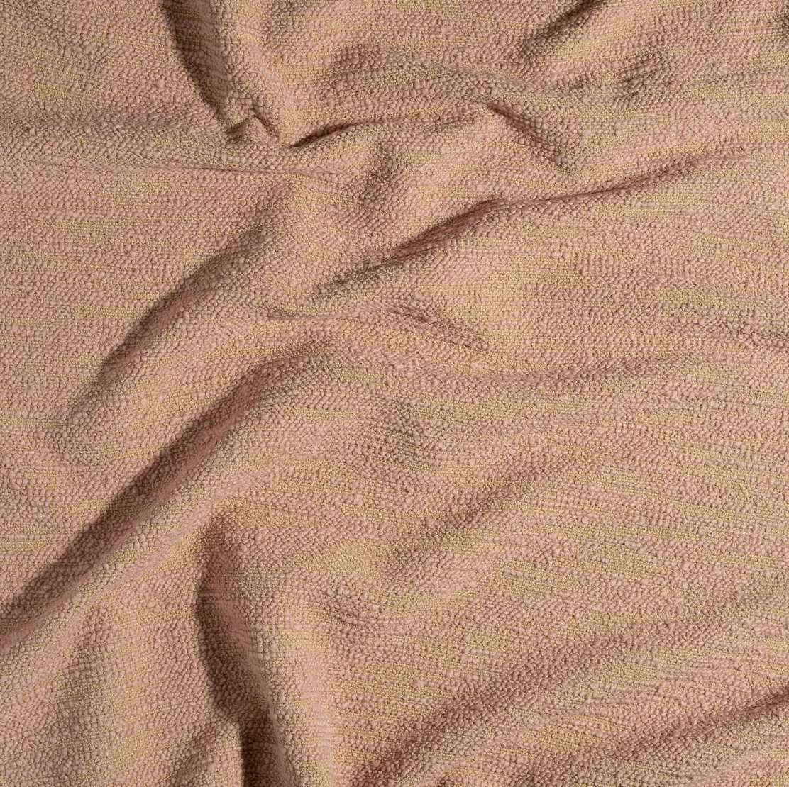 Close-up of a soft, textured fabric in a light pink or beige color, with gentle folds and creases.