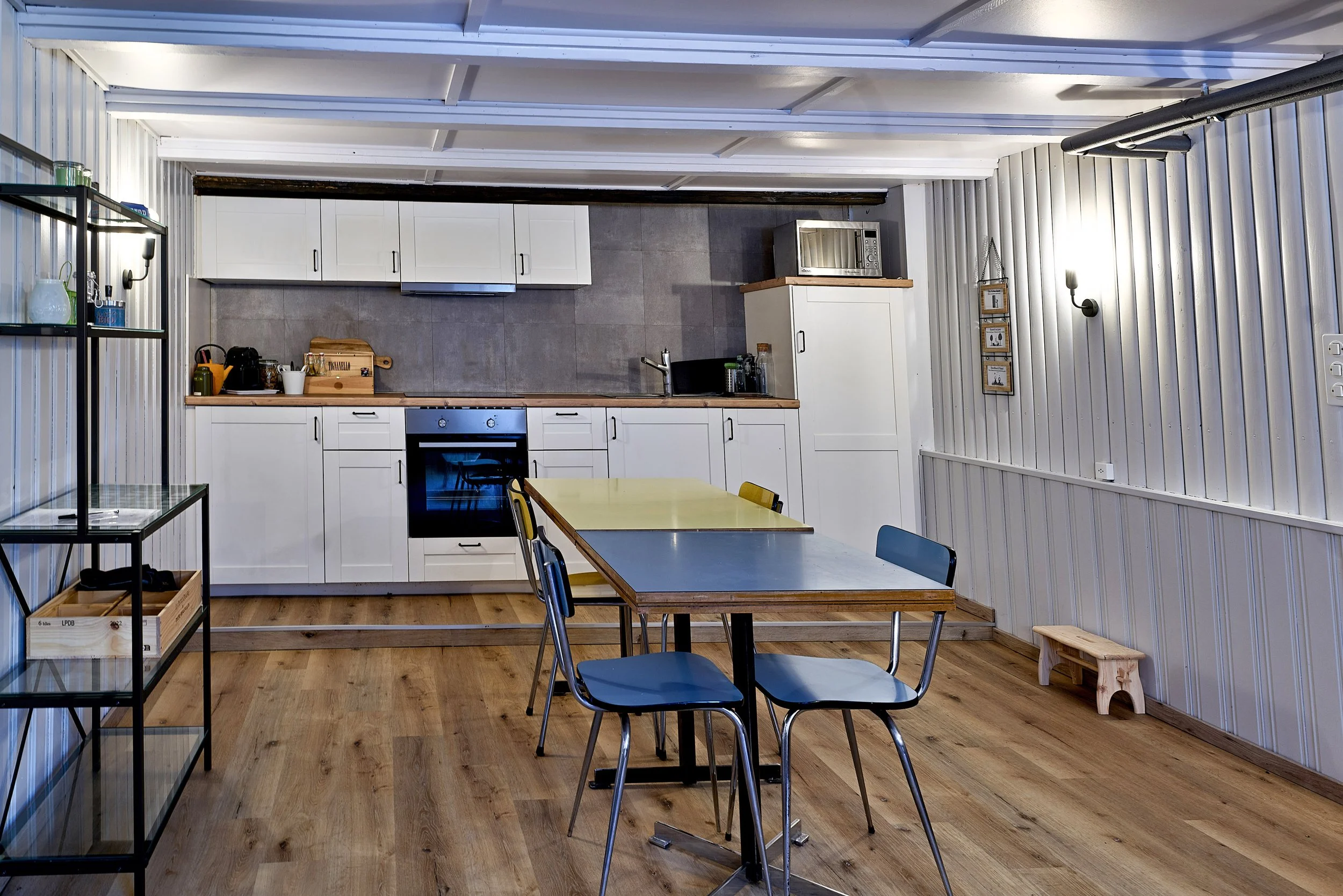 Cuisine moderne avec plan de travail, four, micro-ondes, vitrocéramique, micro-onde, armoires, table en formica avec chaises, jaunes et bleues, sol en bois.