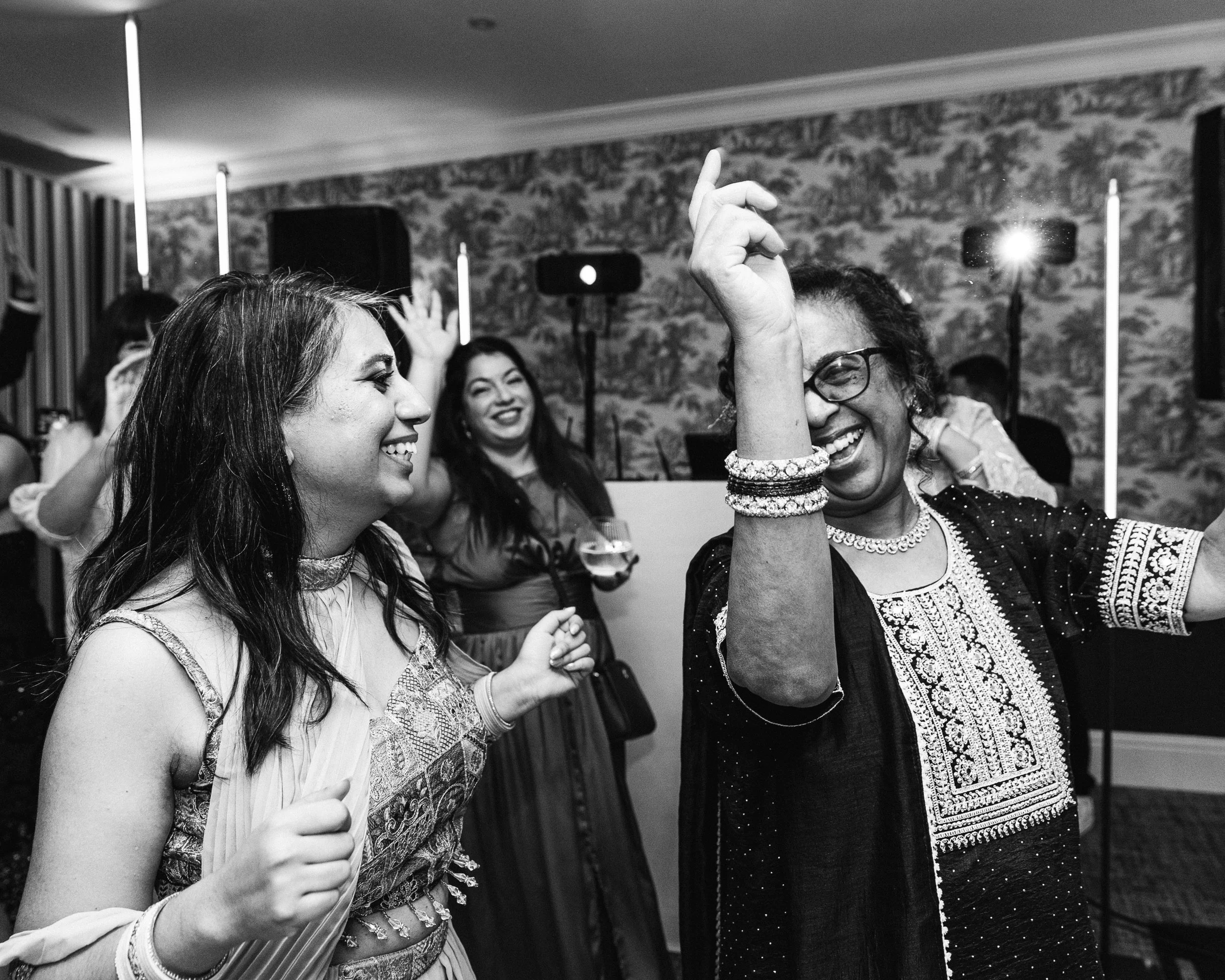Mum and Daughter on the dancefloor smiling in traditional Indian wedding attire at this Anglo-Asian fusion wedding in Buckinghamshire