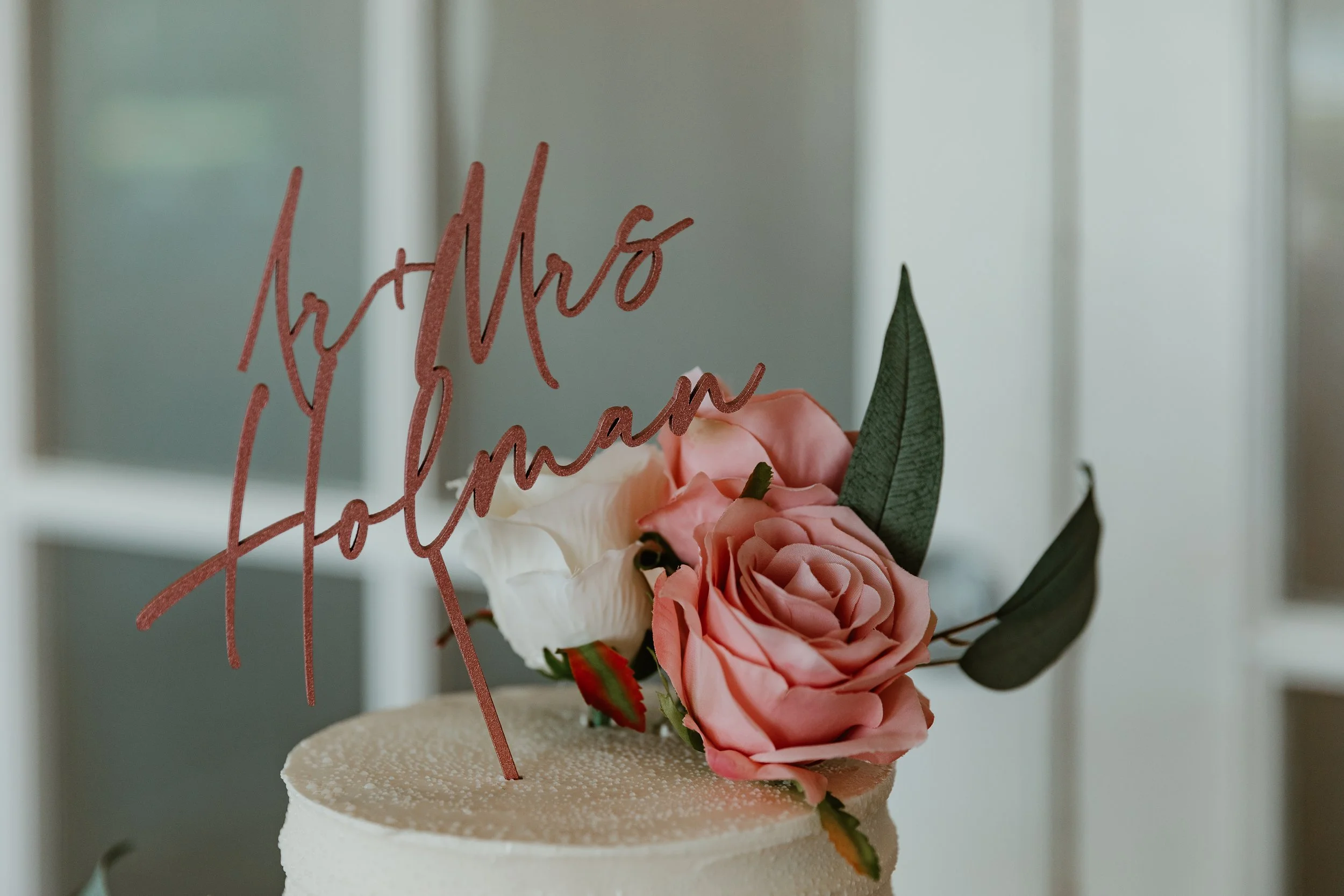 Top of a decorated wedding cake with flowers and "Mr & Mrs"