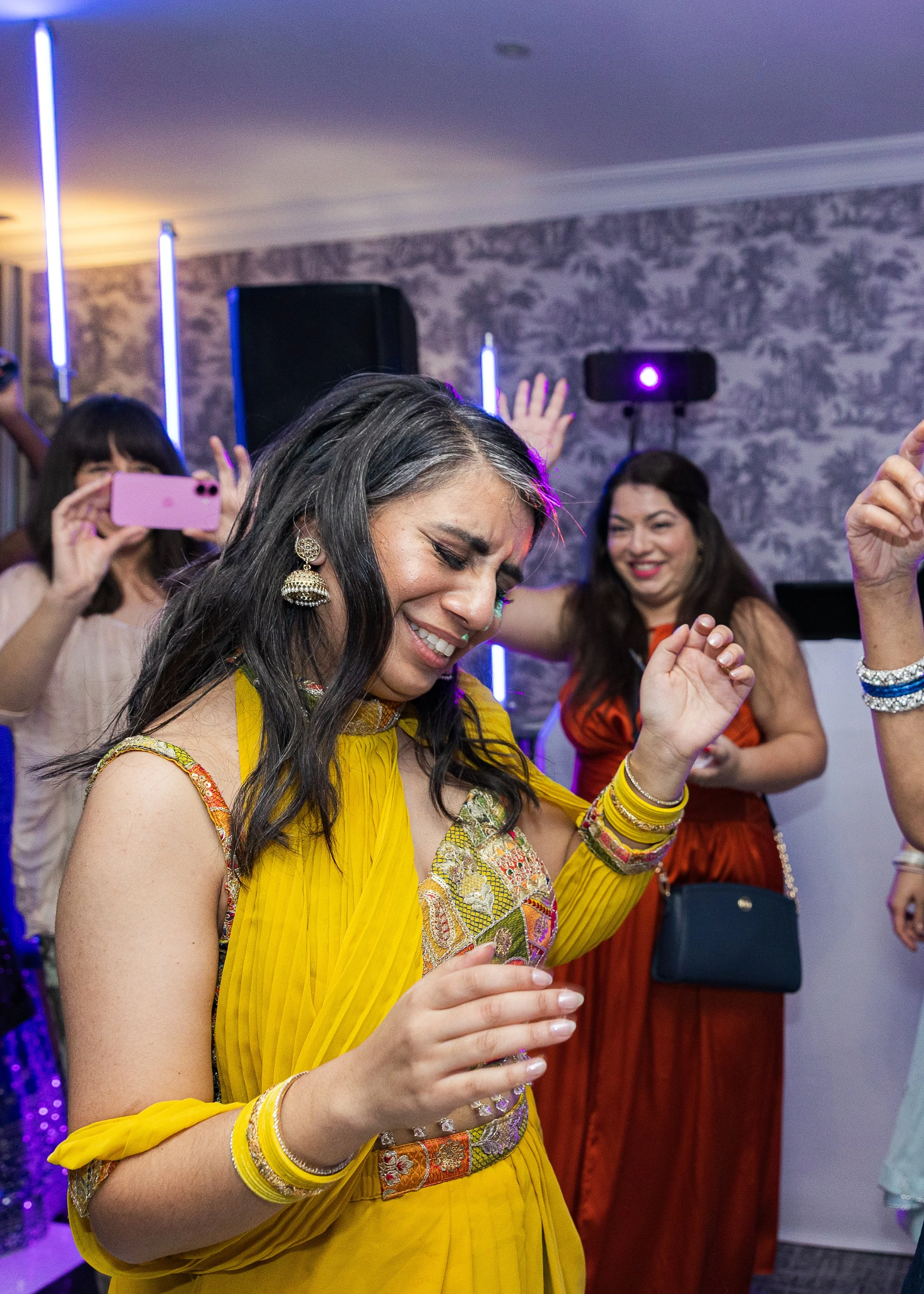 Bride on the dancefloor with her hands in their, wearing traditional Indian wedding attire at this Anglo-Asian fusion wedding in Buckinghamshire