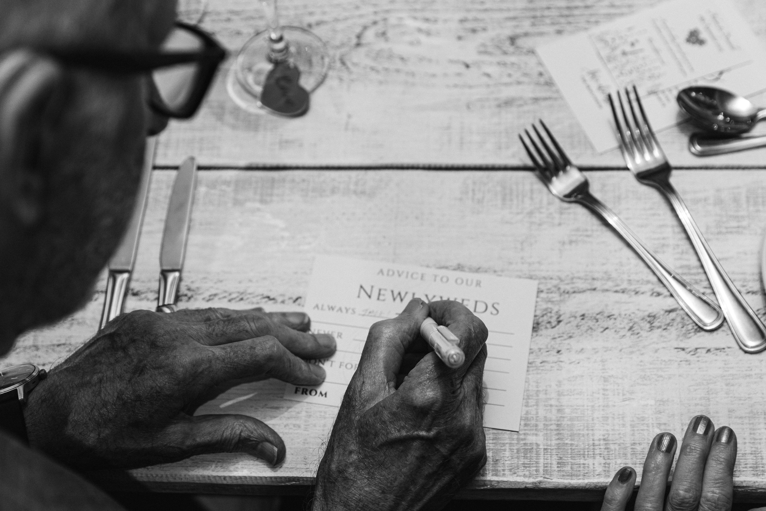 Older gentlemen filling in an advice card for newly weds at their Hertfordshire wedding