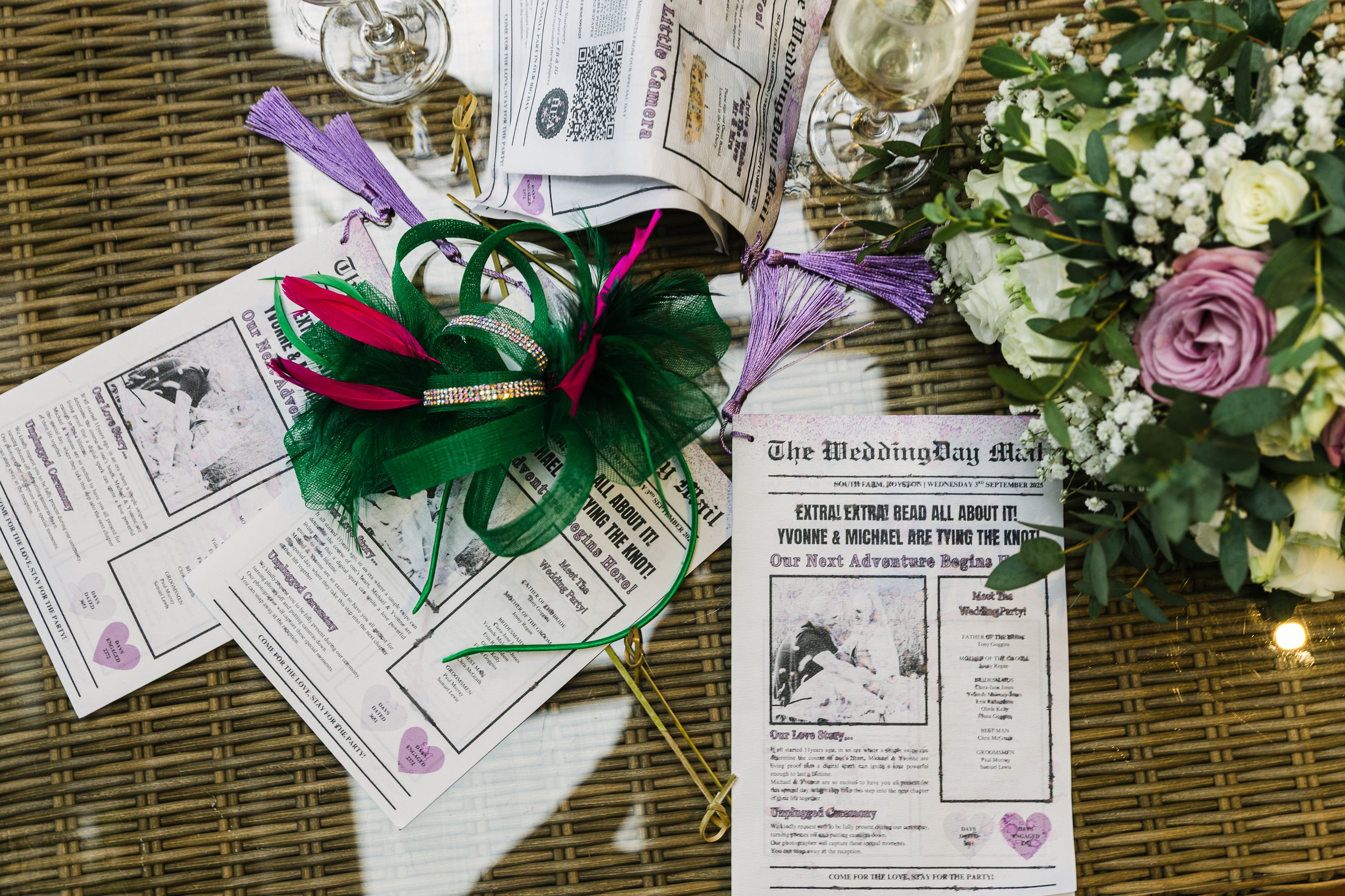 A soggy gathering of wedding literature under a green fascinator and bridesmaid bouquets. Taken at a rainy wedding at South Farm Hertfordshire