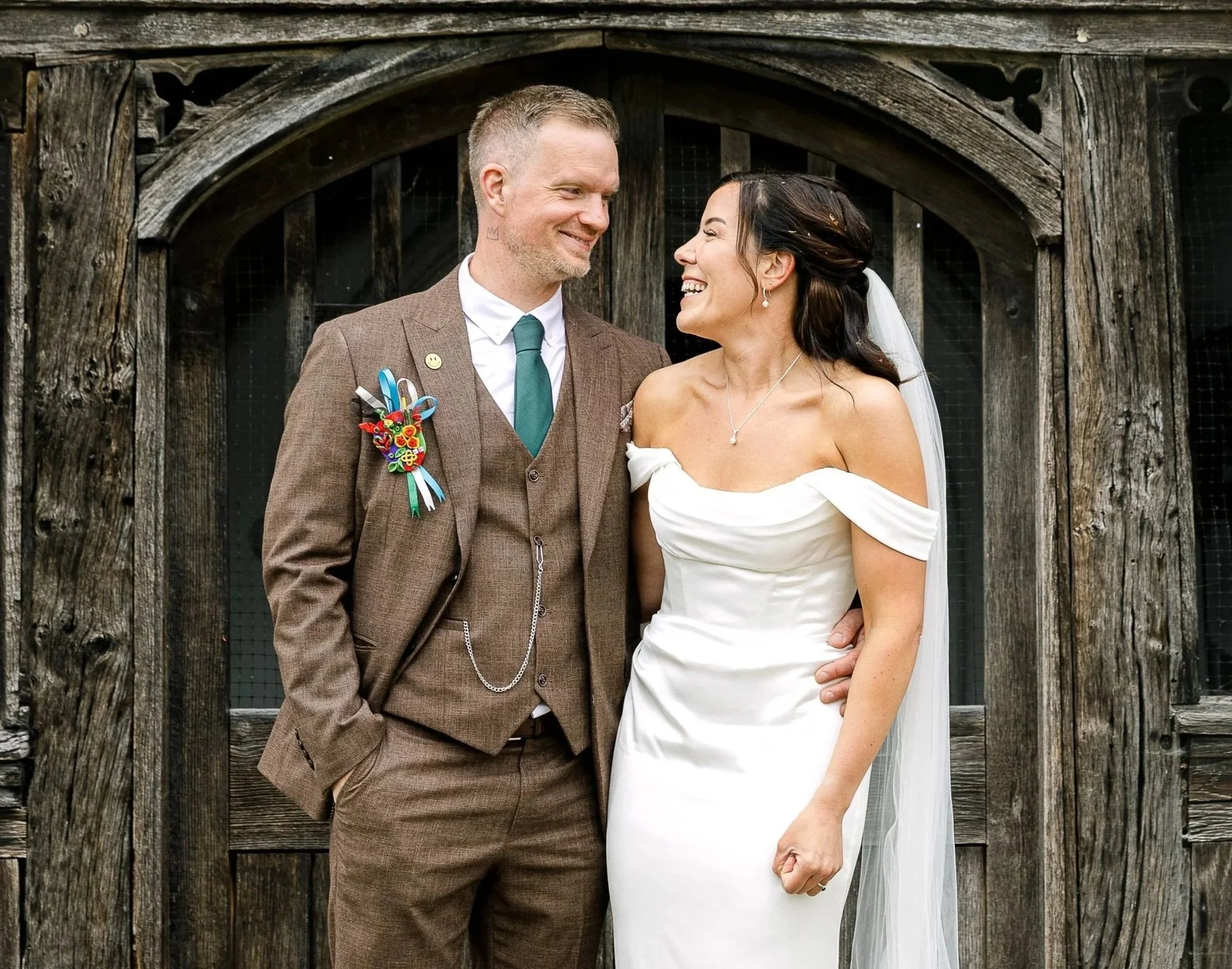 Groom in a light brown suit with his bride in a Grecian style wedding dress