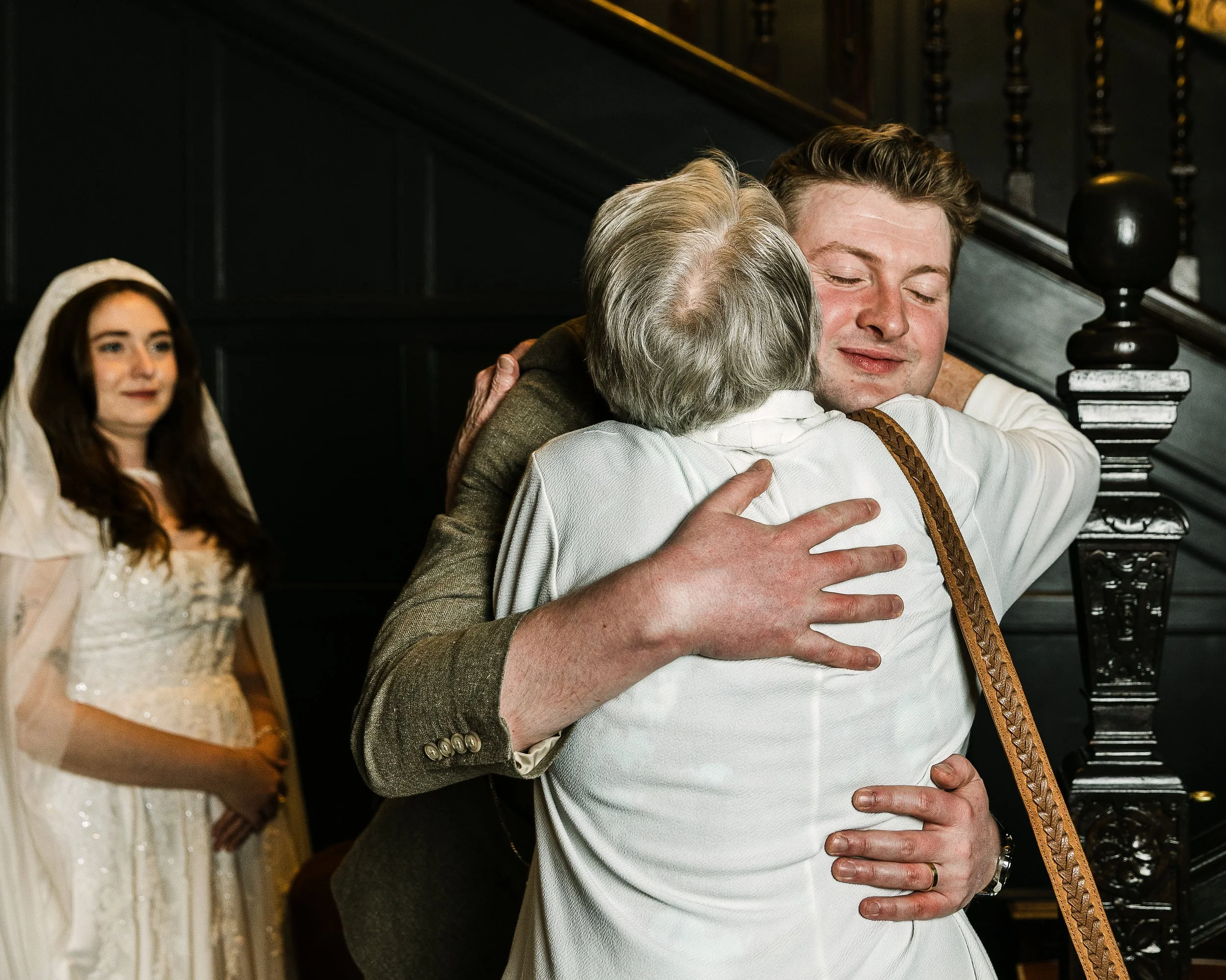 Groom hugging his Grandma as his Bride looks on