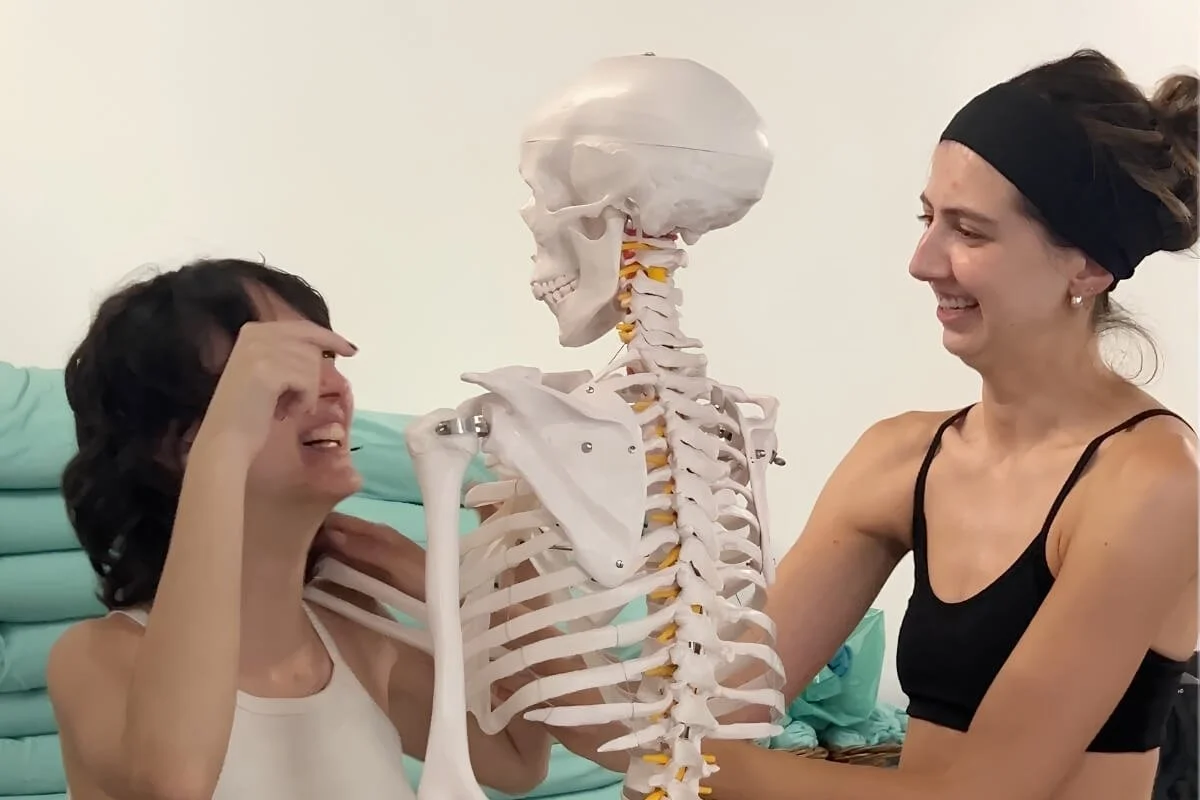 Sarah Kelly laughing and studying anatomy with a fellow yoga teacher trainee during Power to Lead in Lisbon