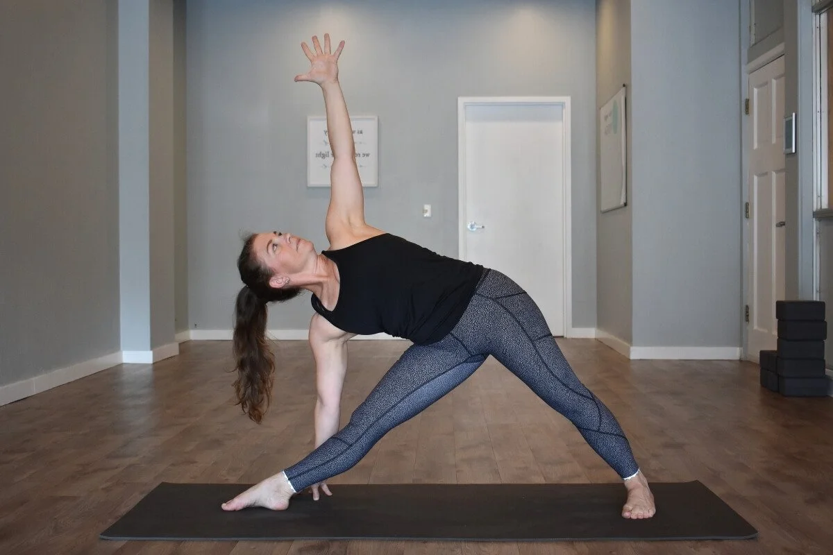Yoga teacher demonstrating proper knee alignment in Triangle pose