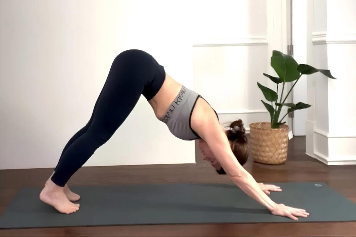 Yoga teacher in downward facing dog with passive lower body showing weight collapsing into the wrists