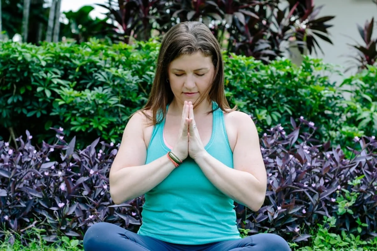 Yoga teacher sitting in meditation outdoors, using practice to build confidence and overcome self-doubt