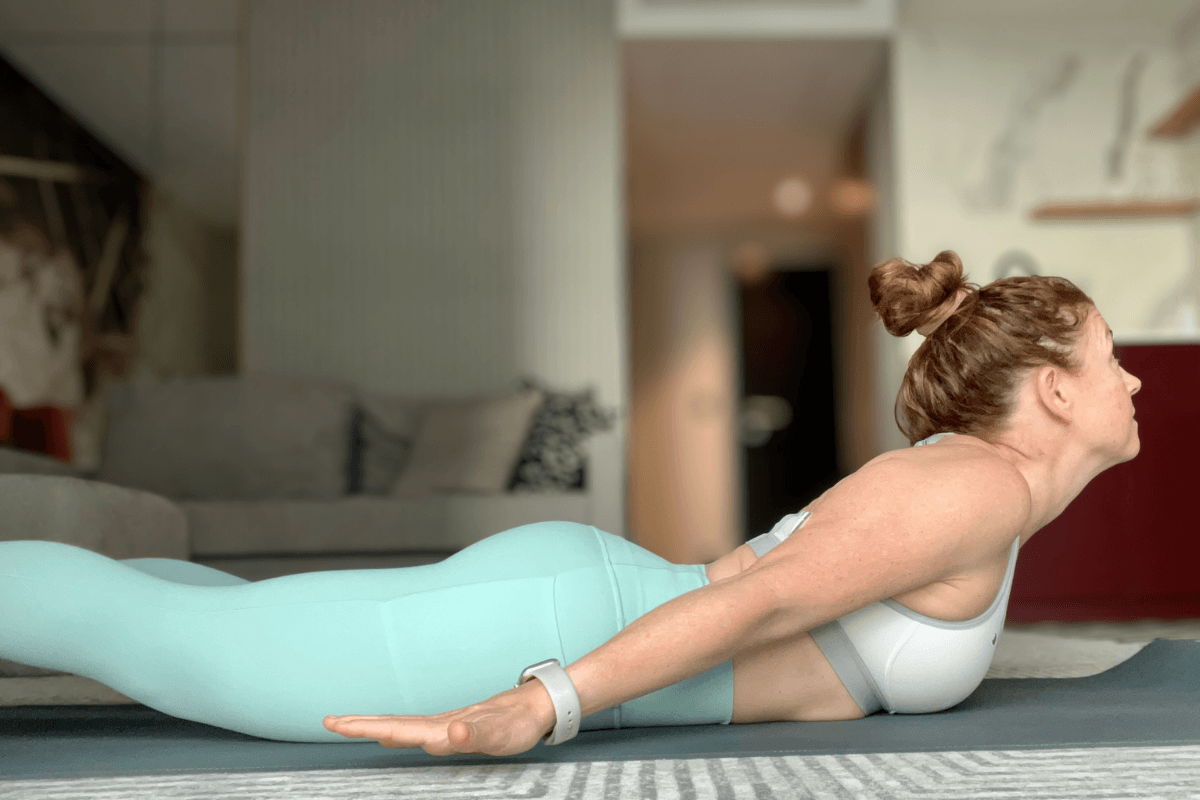 Yoga teacher demonstrating locust pose cues with gaze up showing cervical spine compression