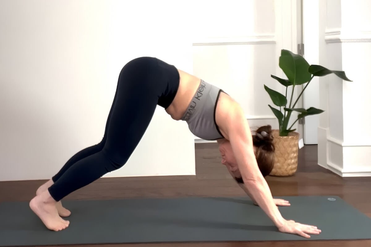 Yoga teacher in downward facing dog with passive lower body showing weight collapsing into the wrists