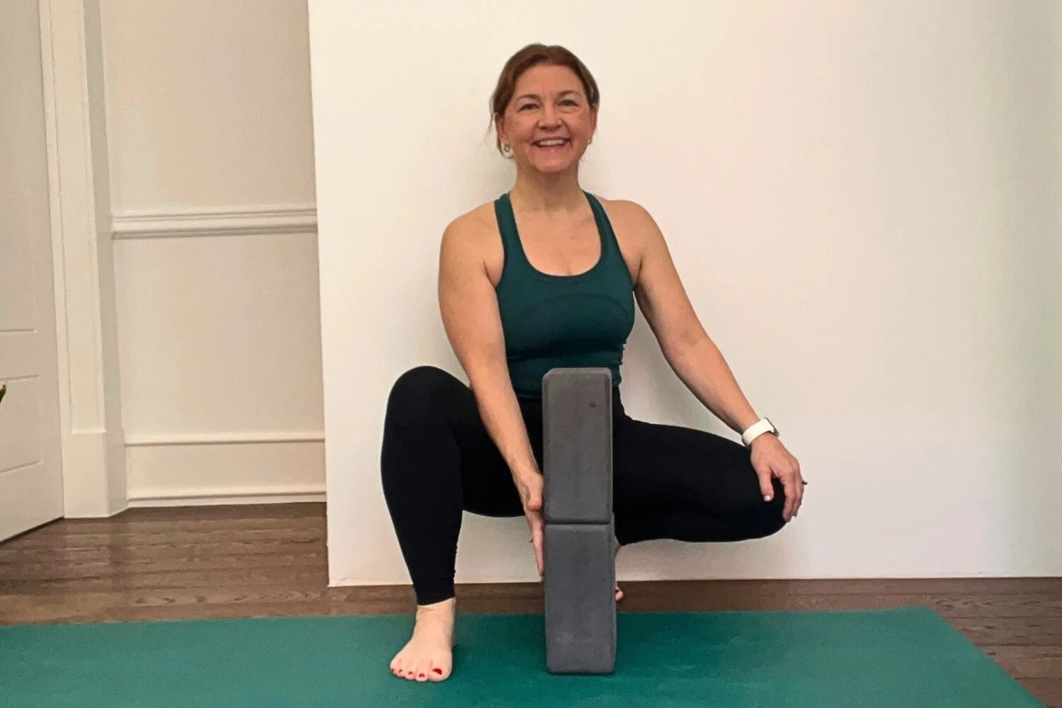Two yoga blocks stacked vertically with hands pressing at the seam to demonstrate knee stability