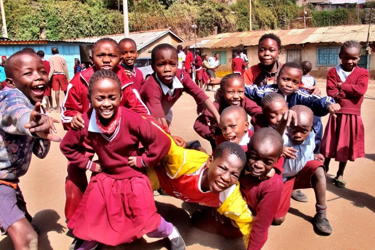 Smiling children in Kenya during a yoga teacher training visit, beyond alignmen