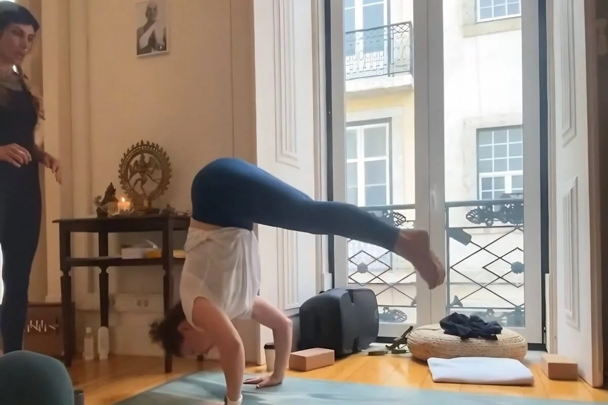 Lita Sattva teaching Dr. Trish Corley in a challenging posture during a Rocket Yoga teacher training in Lisbon