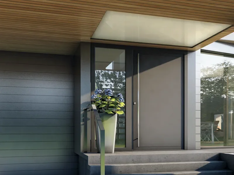 Entrada de una casa moderna con puerta gris y un florero con flores en la entrada.