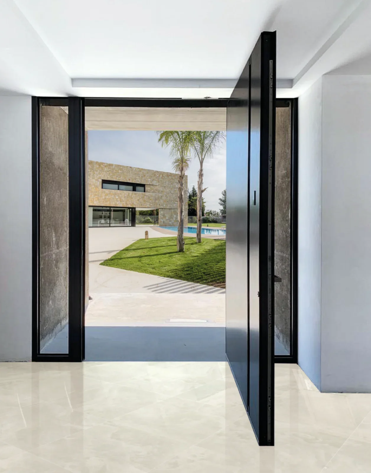 Puerta mitocoulo abierta que da al jardín y alberca de una casa moderna