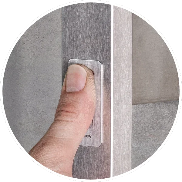 Dedo presionando un botón en un marco de metal, probablemente en una máquina o equipo.