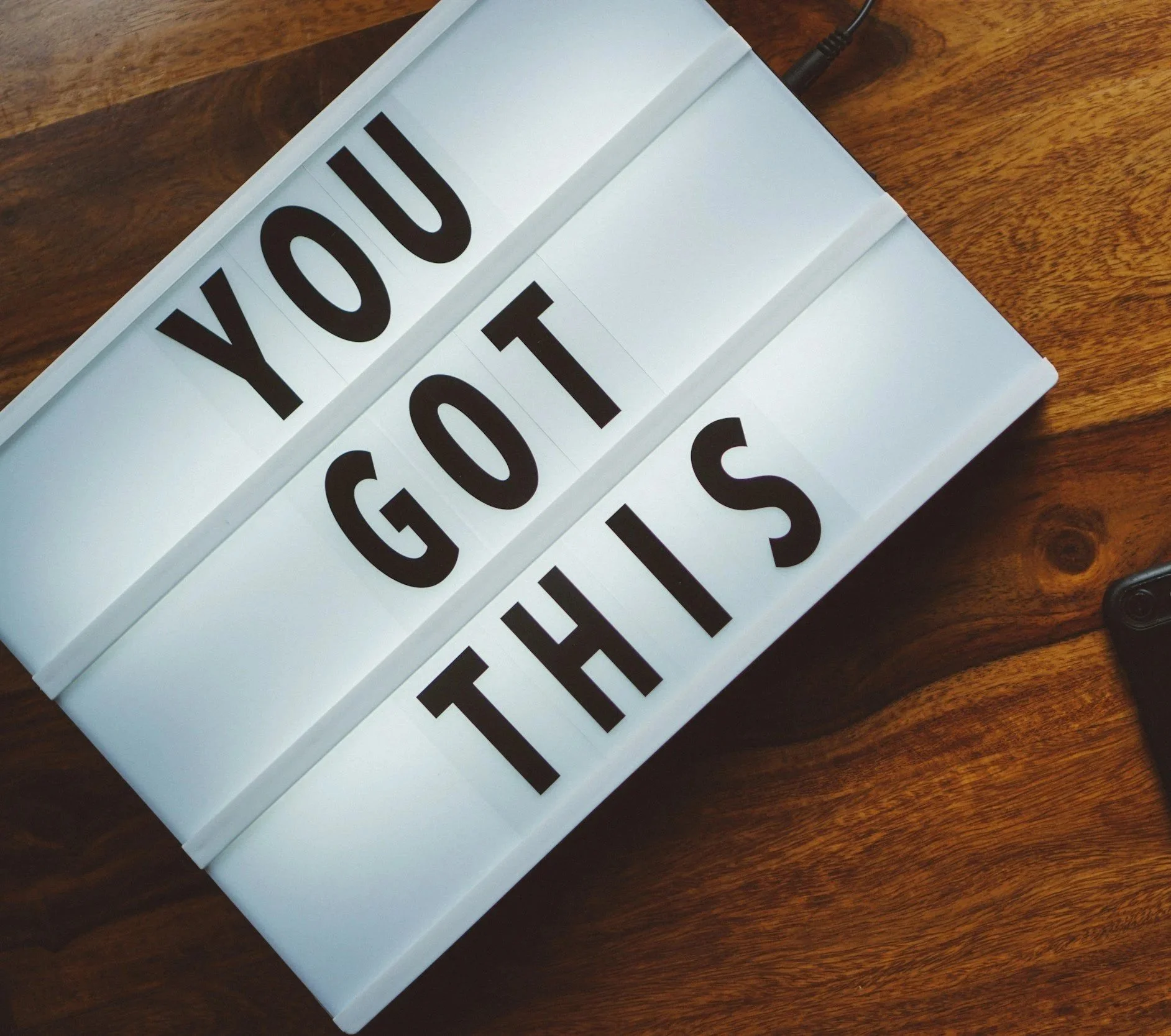 Lightbox sign with black letters reading 'YOU GOT THIS' on a wooden surface.