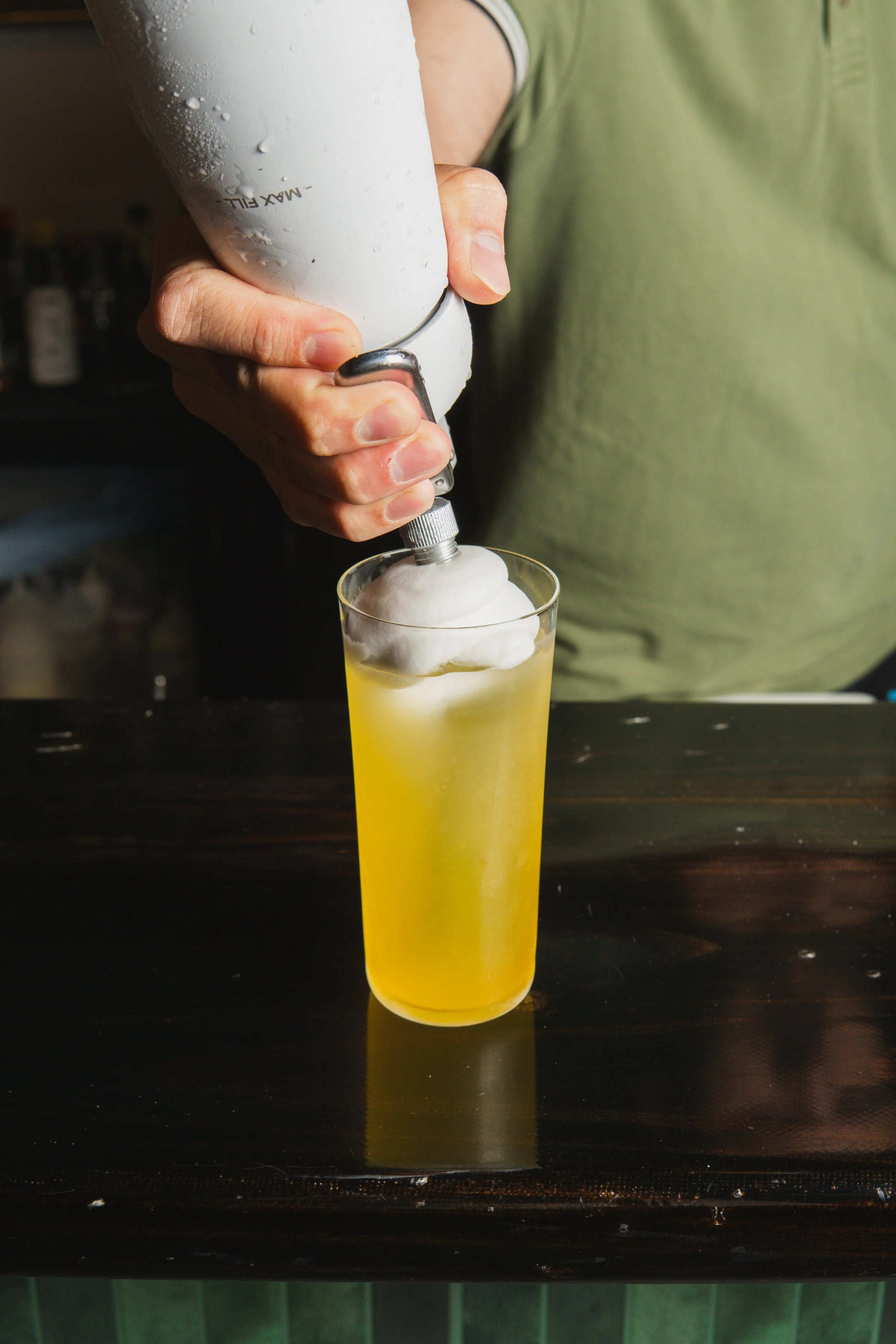Close up photo of bartender putting the finishing touches on a Mando Cloud cocktail with coconut foam on top