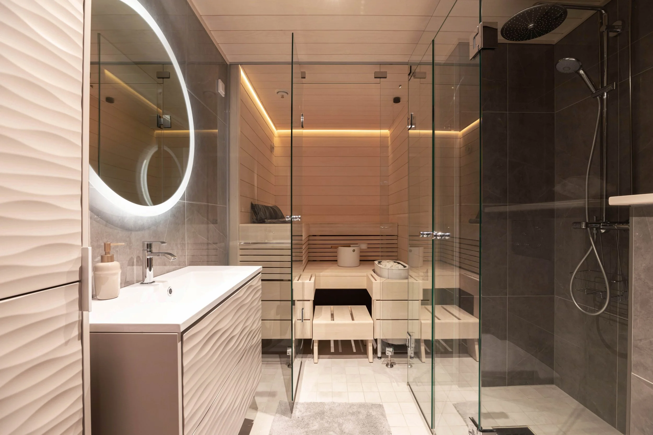 Moderni kylpyhuone, jossa lavrenträmainen suihku, iso peili ja pesuallas.