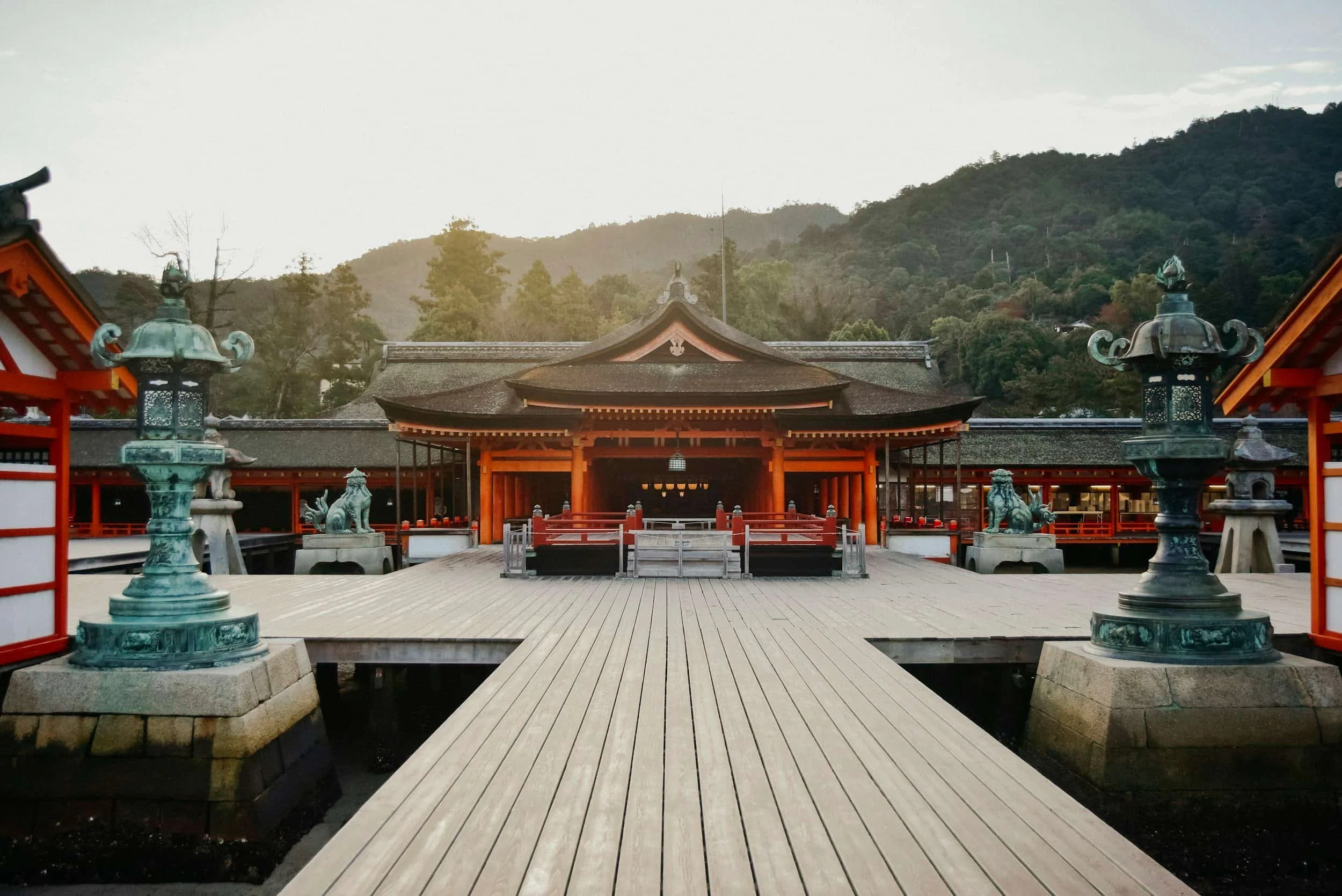 Temple japonais avec pont en bois et lanternes, décor de montagne, visite incontournable au Japon.
