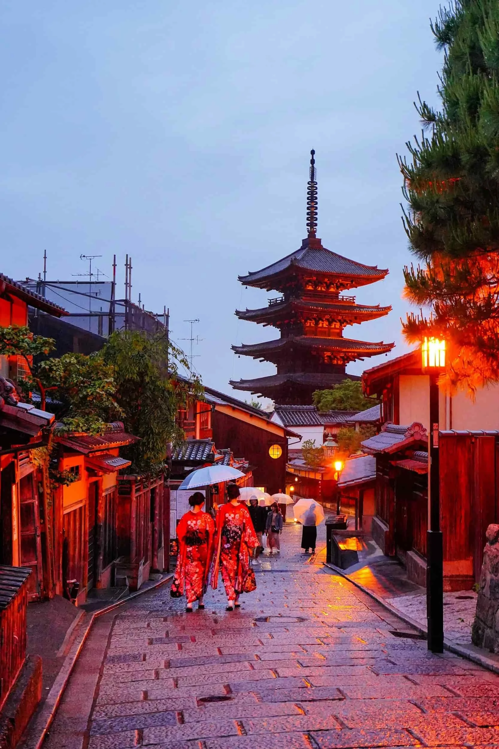 Rue pavée avec kimonos et pagode au crépuscule, quartier traditionnel au Japon.